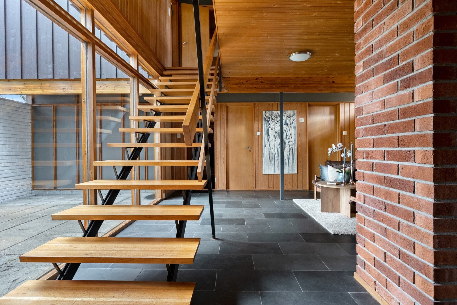 Kjellerstuen med trapp til 2. etasje og store vinduer mot "skogen". Galleribilde