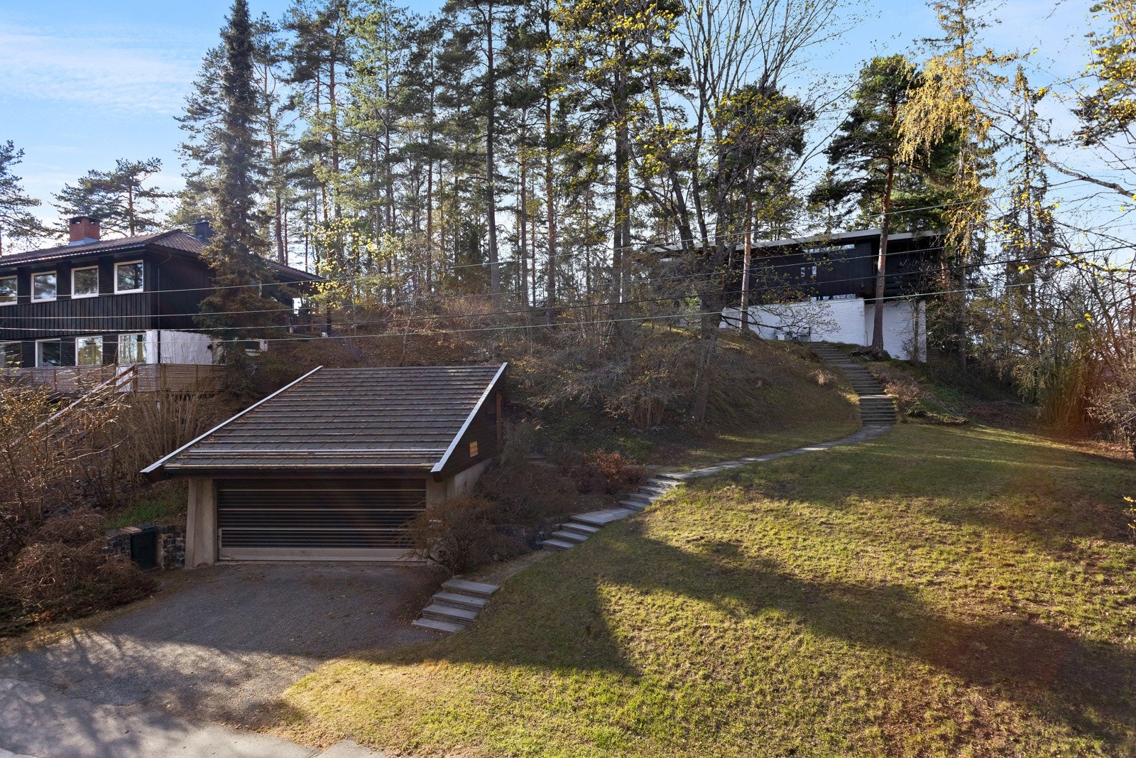 Eiendommen er terrassert opp fra vei og garasje med trappeadkomster, gangvei, uteplasser, grøntareal og beplantning. Deler av eiendommen er naturtomt. Galleribilde