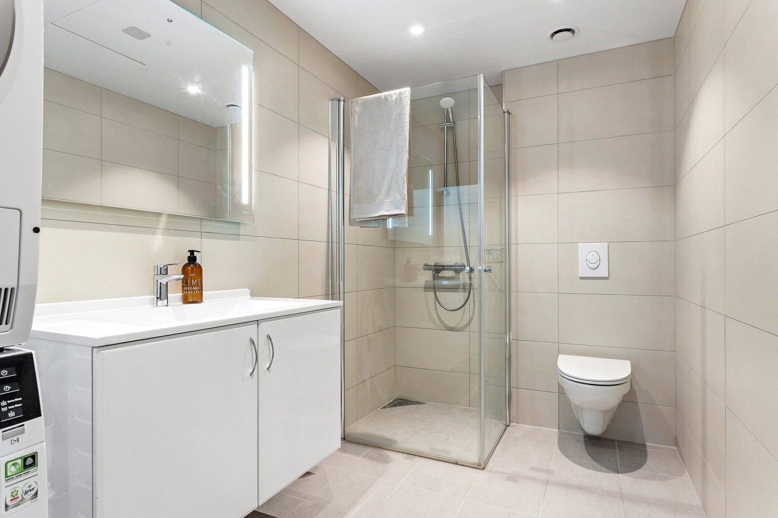 Badet er lekkert med duse moderne fliser og opplegg til vaskemaskin Galleribilde