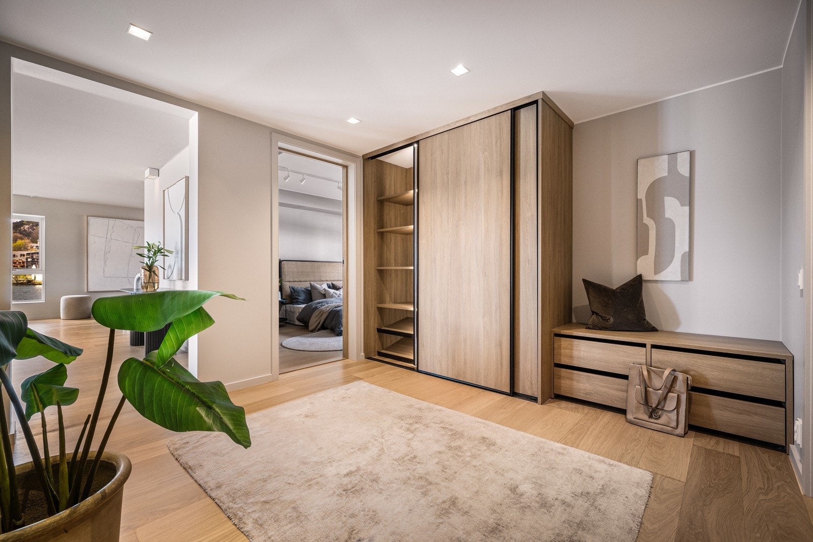 Romslig skyvedørsgarderobe med integrert belysning samt sittebenk med skuffer. Galleribilde