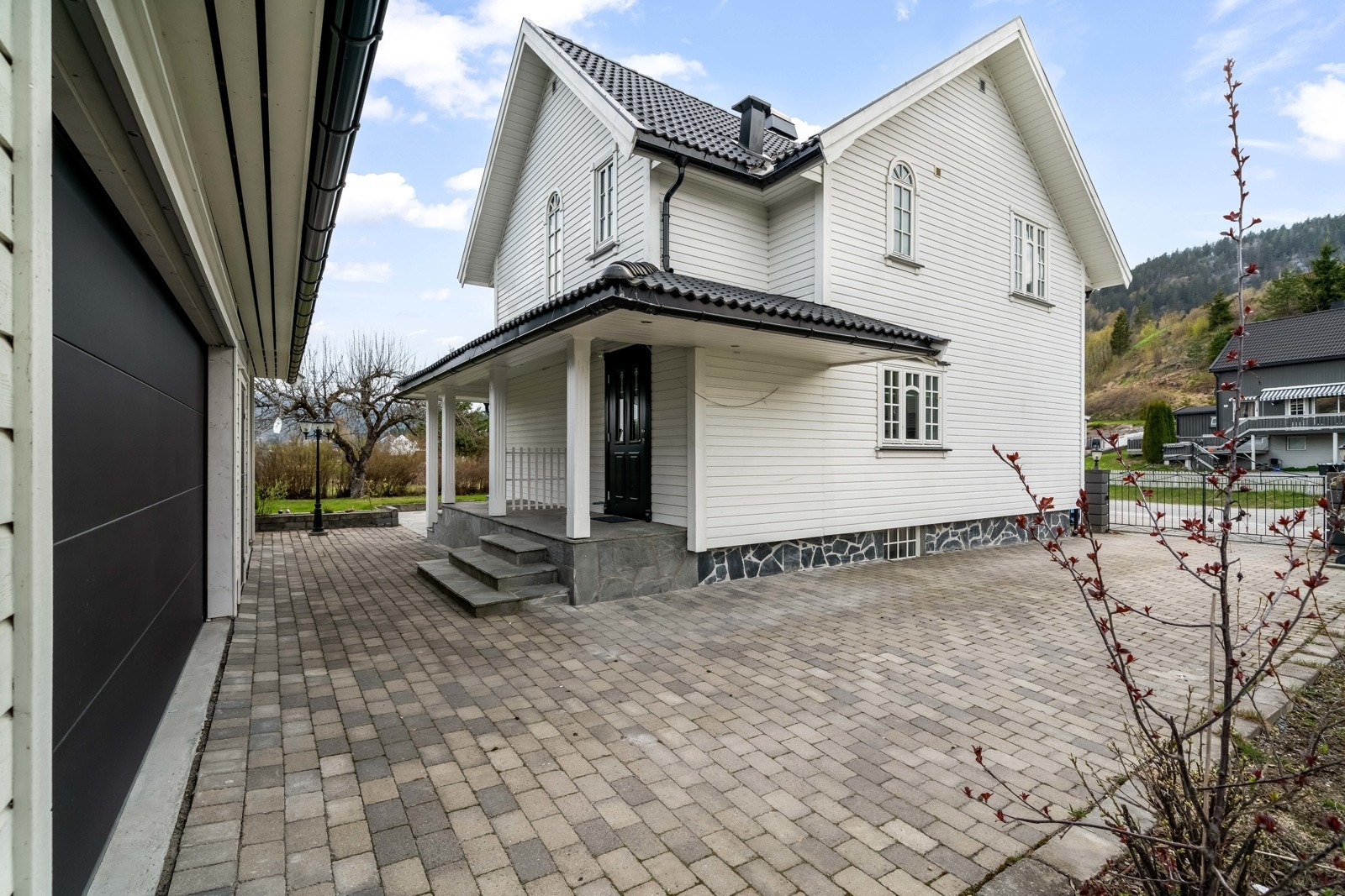Innbydende og delikat inngangsparti med overbygg, trapper, skifer og belegningsstein. Fin belysning på kveldstid. Galleribilde