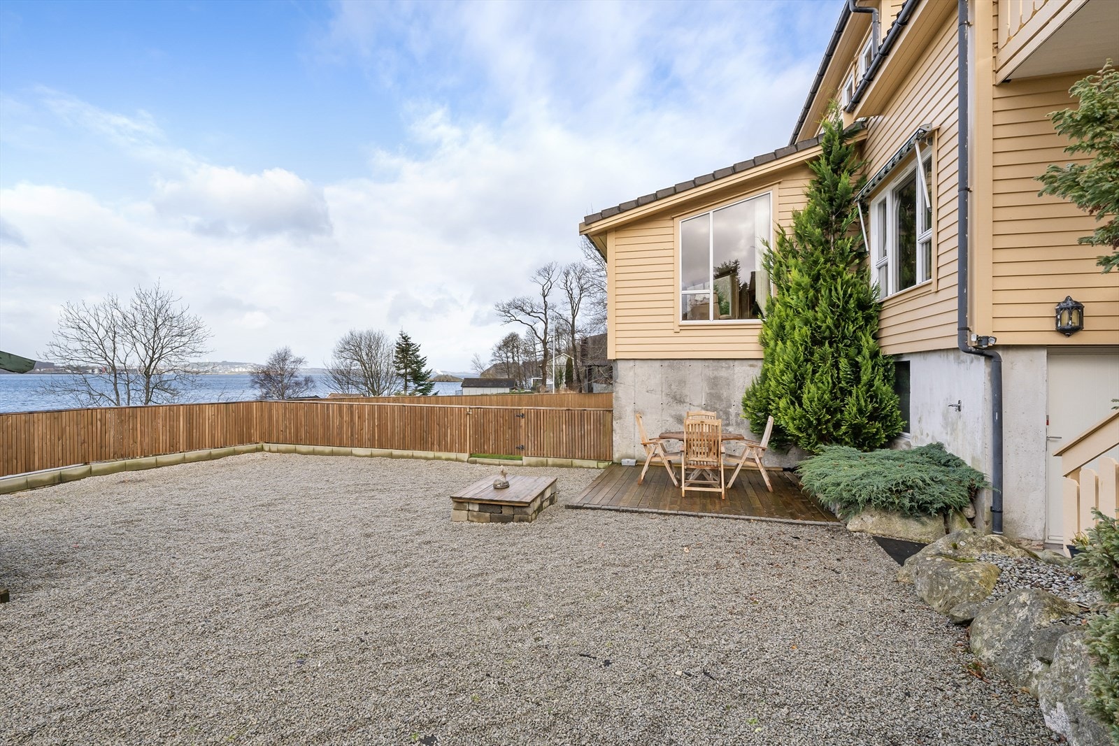 Eiendommen er inngjerdet og delt mellom plen og grusdel. Utgang ned port fra hagen mot sjøen. Galleribilde