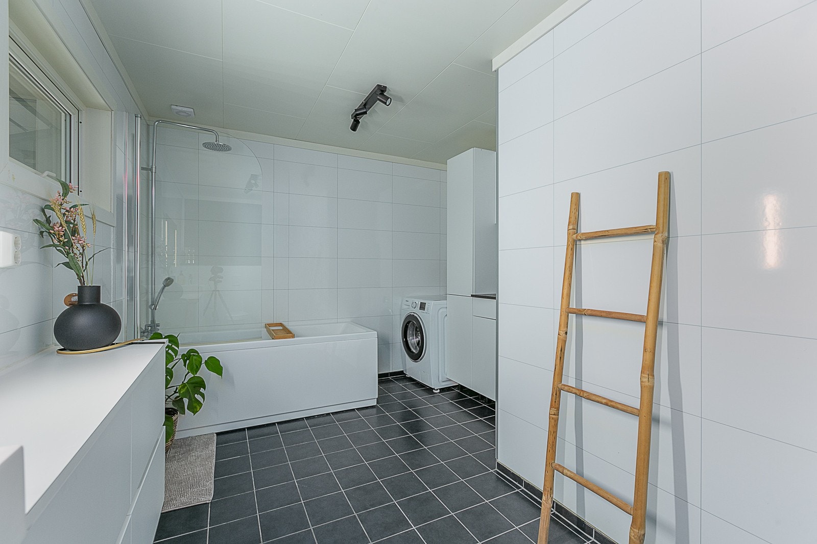 Stort bad med opplegg for vaskemaskin og oppbevaring i innredning. Galleribilde