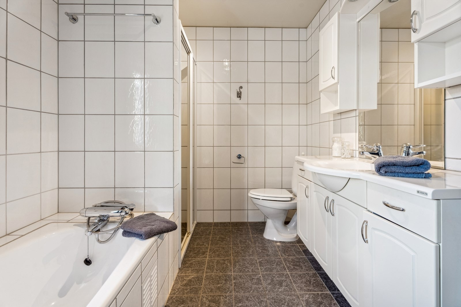 Lyst flislagt bad med heildekkande servant, badekar og dusj. Galleribilde