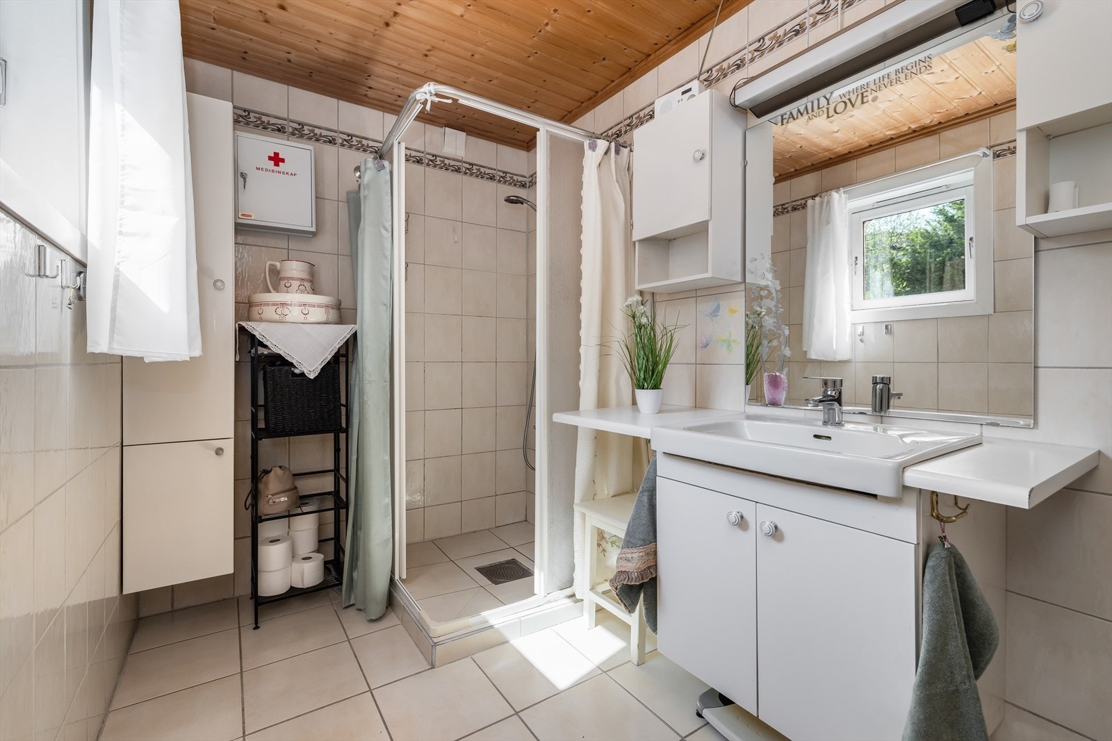 Eldre bad med flis på gulv og vegger. Her er det toalett, dusjnisje med skyvedører og innredning. Det er naturlig ventilering og varmekabler i gulv. Galleribilde