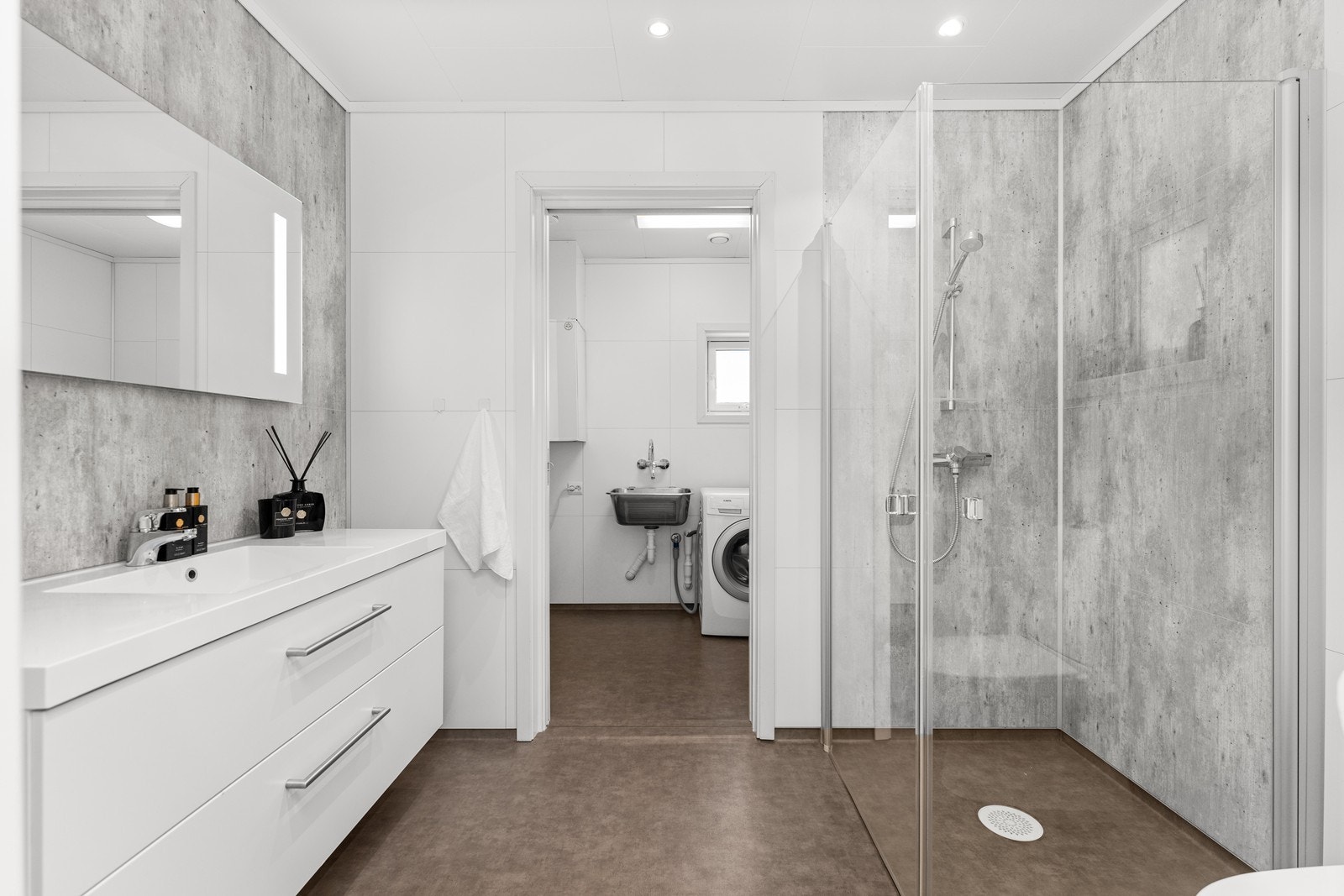 Bad med tilhørende vaskerom/ teknisk rom. Bad har dusj på gulv, servant og wc Galleribilde