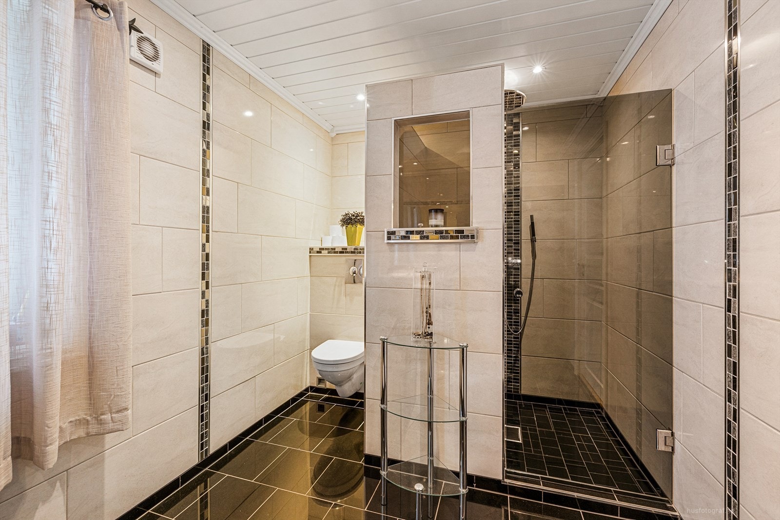 Badet har pen innredning med nedfelt dobbel servanter, veggmontert toalett og dusjnisje. Galleribilde