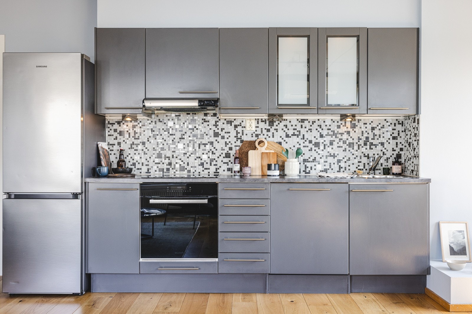 Praktisk kjøkken med integrerte hvitevarer som platetopp, stekeovn og oppvaskmaskin. Frittstående kjøleskap. Galleribilde