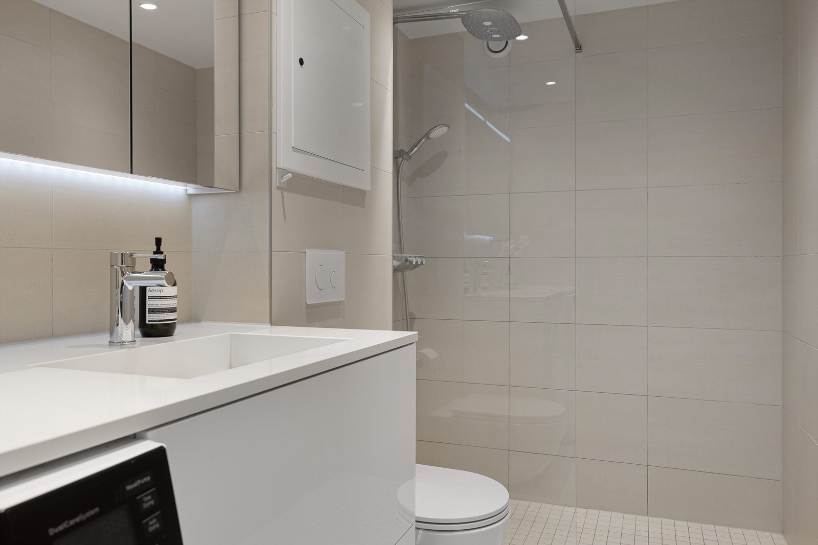 Dusjvegg i glass skjermer dusjsonen fra resten av badet. Det er dimbare downlights i himling, og varme i gulv. Galleribilde