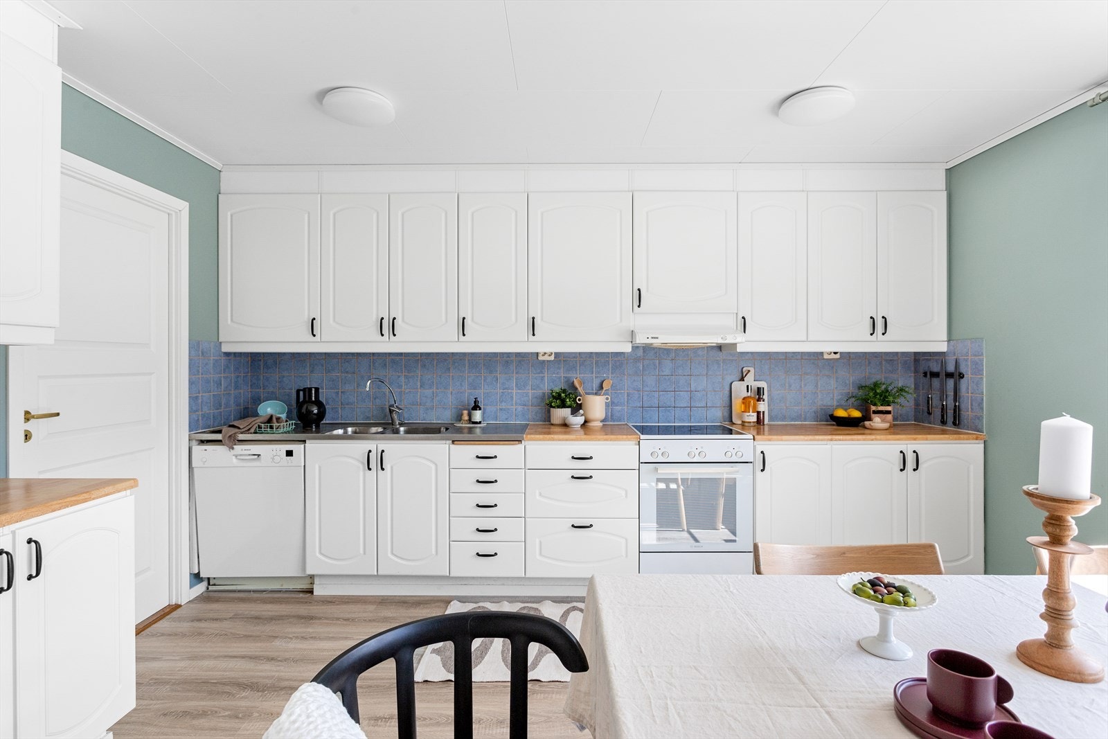 Kjøkkeninnredningen består av skap med hvite, profilerte fronter og benkeplate av laminat. Galleribilde