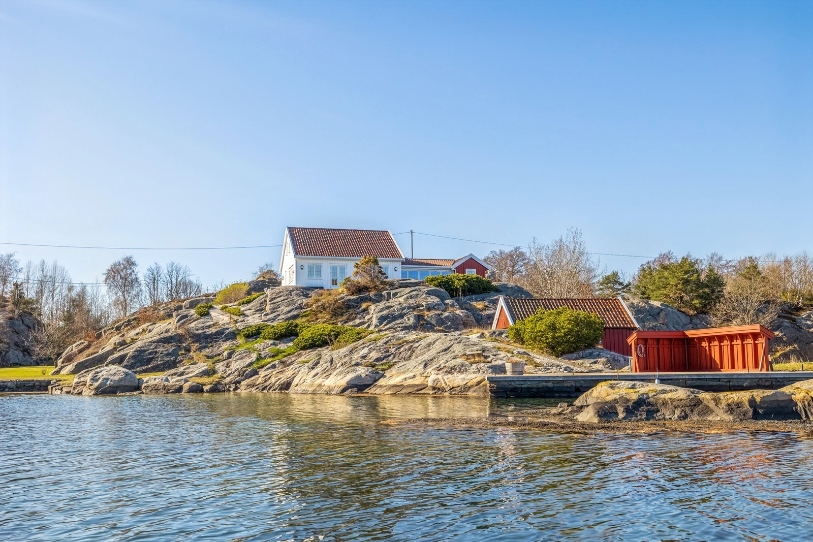 Stedet ligger usjenert til i le for sydvesten. Den lille holmen nærmest bryggen hører til eiendommen . Galleribilde