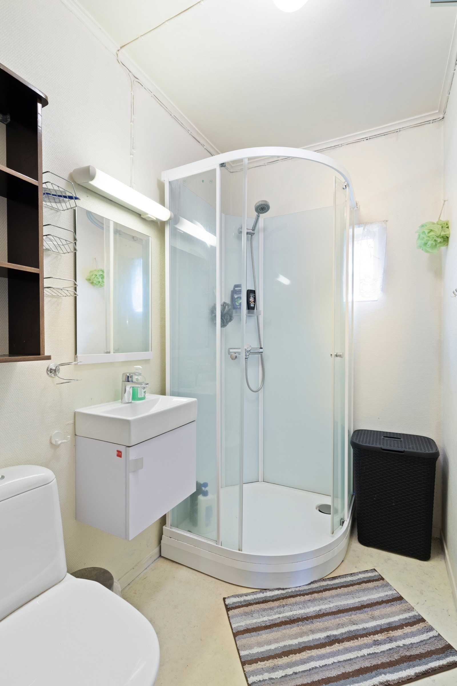 Badet i hovedetasjen har belegg på gulv og malte flater på veggene. Rommet er utstyrt med toalett, dusjkabinett og baderomsinnredning med servant. Kabinett, servant og toalett ble utskiftet i 2021. Det ble samtidig lagt ny sluk og nytt avløpsrør. Galleribilde