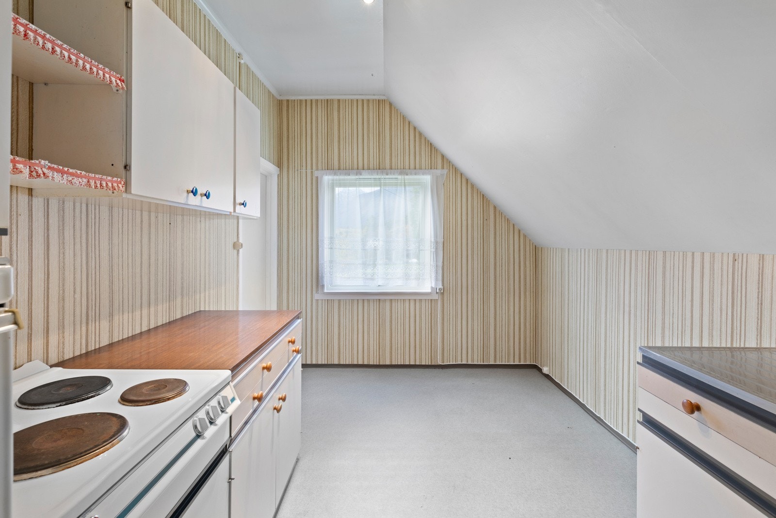 Etasjen har et enkelt kjøkken med hvite fronter, laminat benkeplate, komfyr, utslagsvask og oppvaskkum. Galleribilde