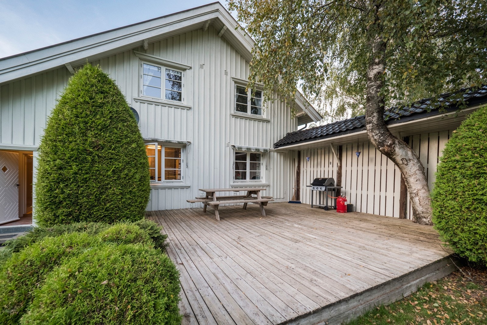 Våningshuset er omkranset av grøntarealer, blomsterbedd og prydbusker Galleribilde