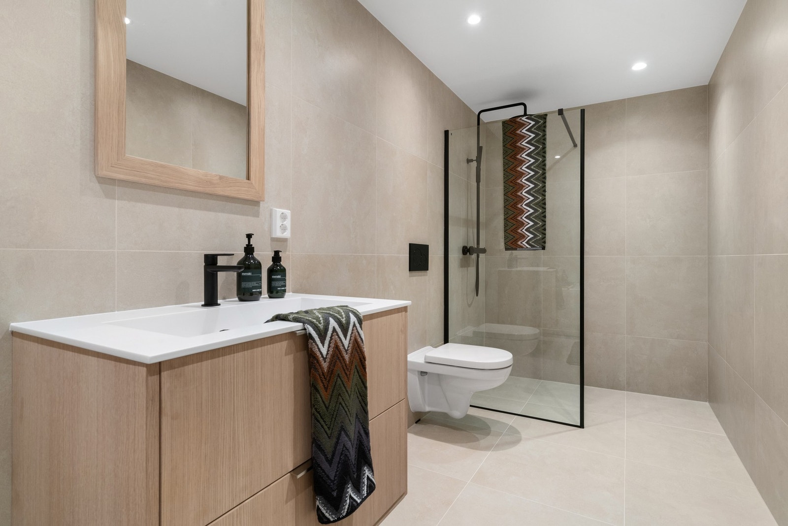 Pent flislagt baderom med dusjhjørne, vegghengt toalett og badekar Galleribilde