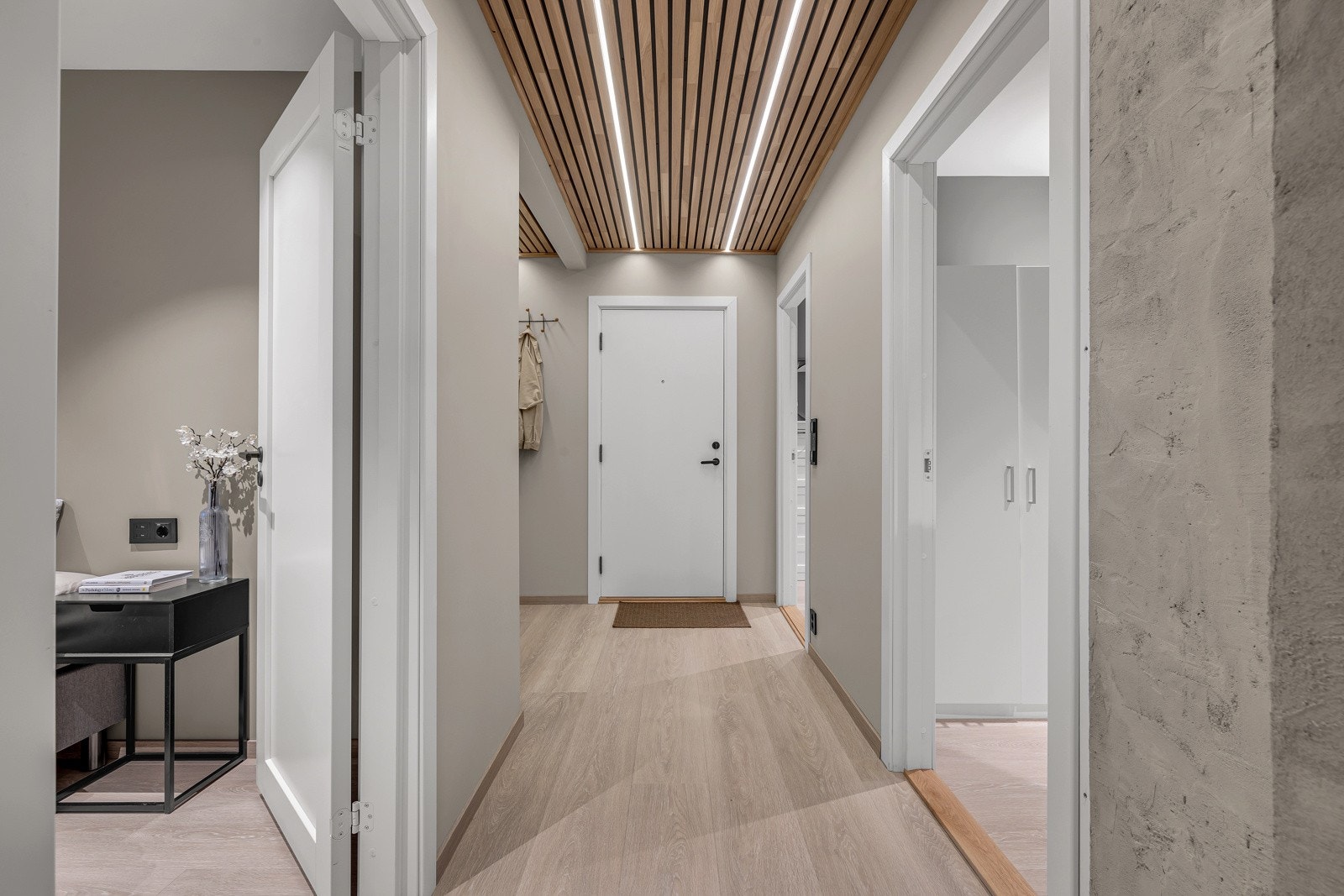 Hele leiligheten har et moderne uttrykk, noe som kommer til syne allerede i entreen. Her er det enstavs laminatgulv med varmefolie, slette, beigemalte vegger og en lekker spilehimling med innfelte LED-striper. Galleribilde