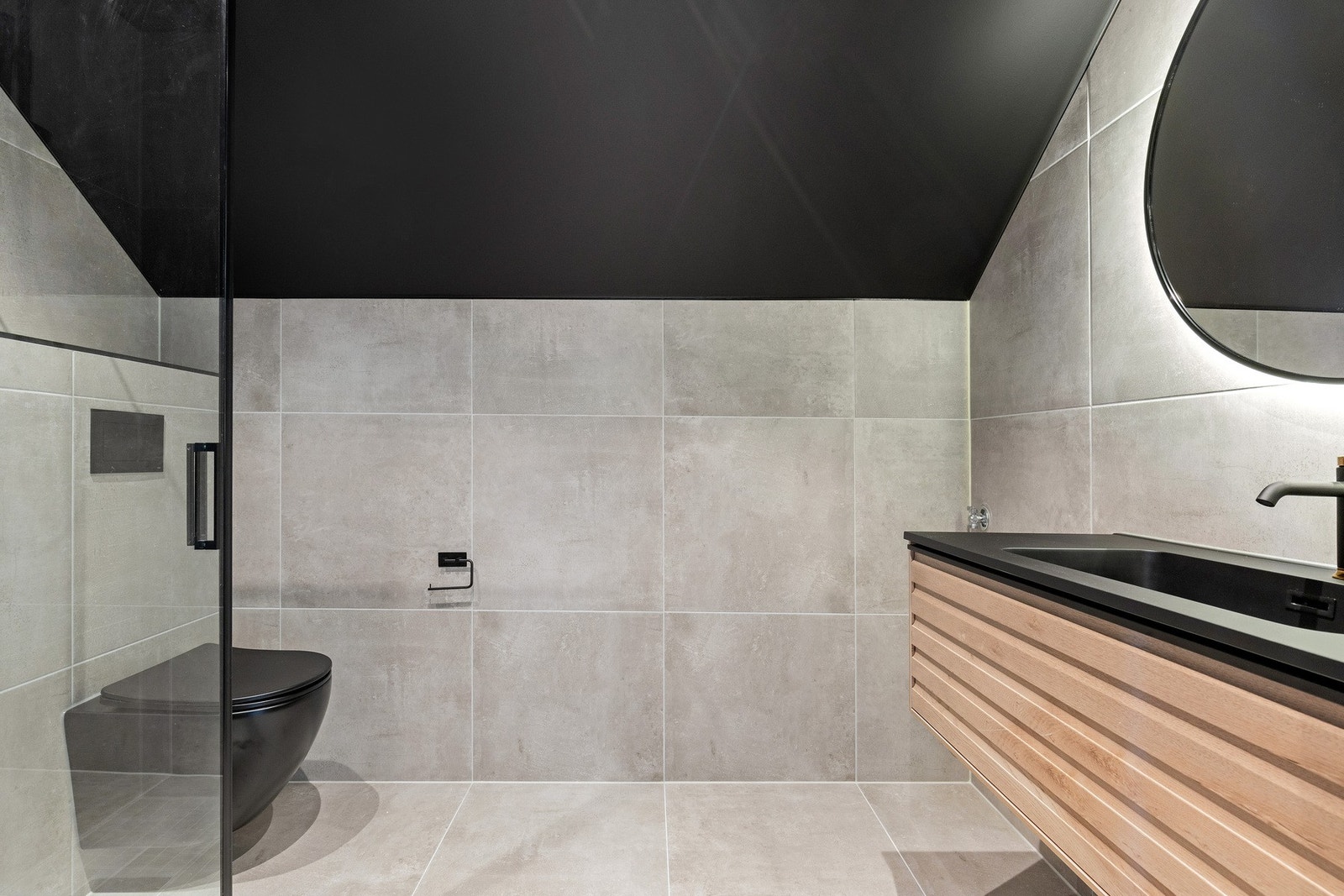 Badet er flislagt og utstyrt med vegghengt toalett, varmekabler i gulv, regndusj, servant og opplegg til vaskemaskin. Galleribilde