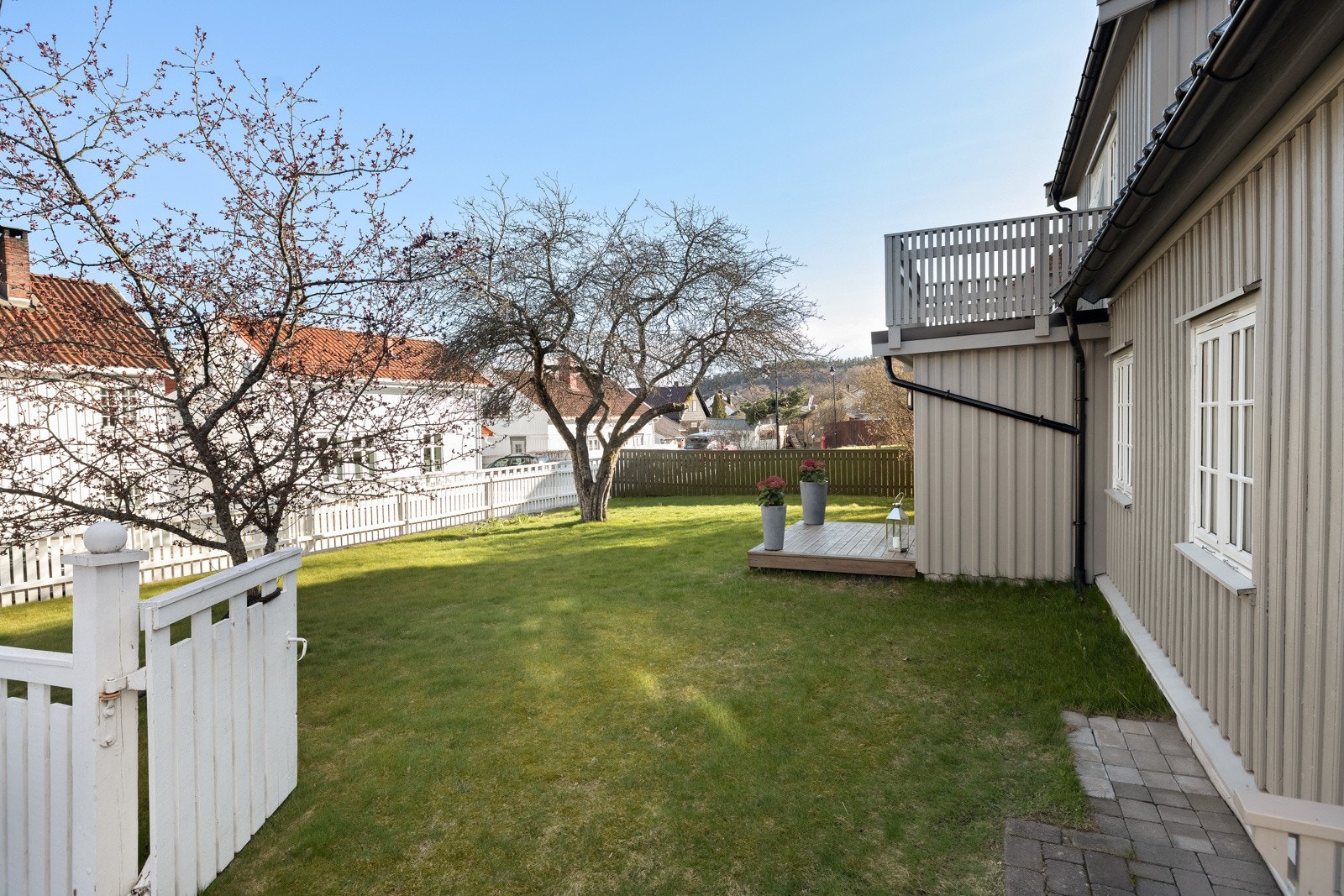 Hagen er en ren idyll med gjerde, gress og vakre trær. Galleribilde