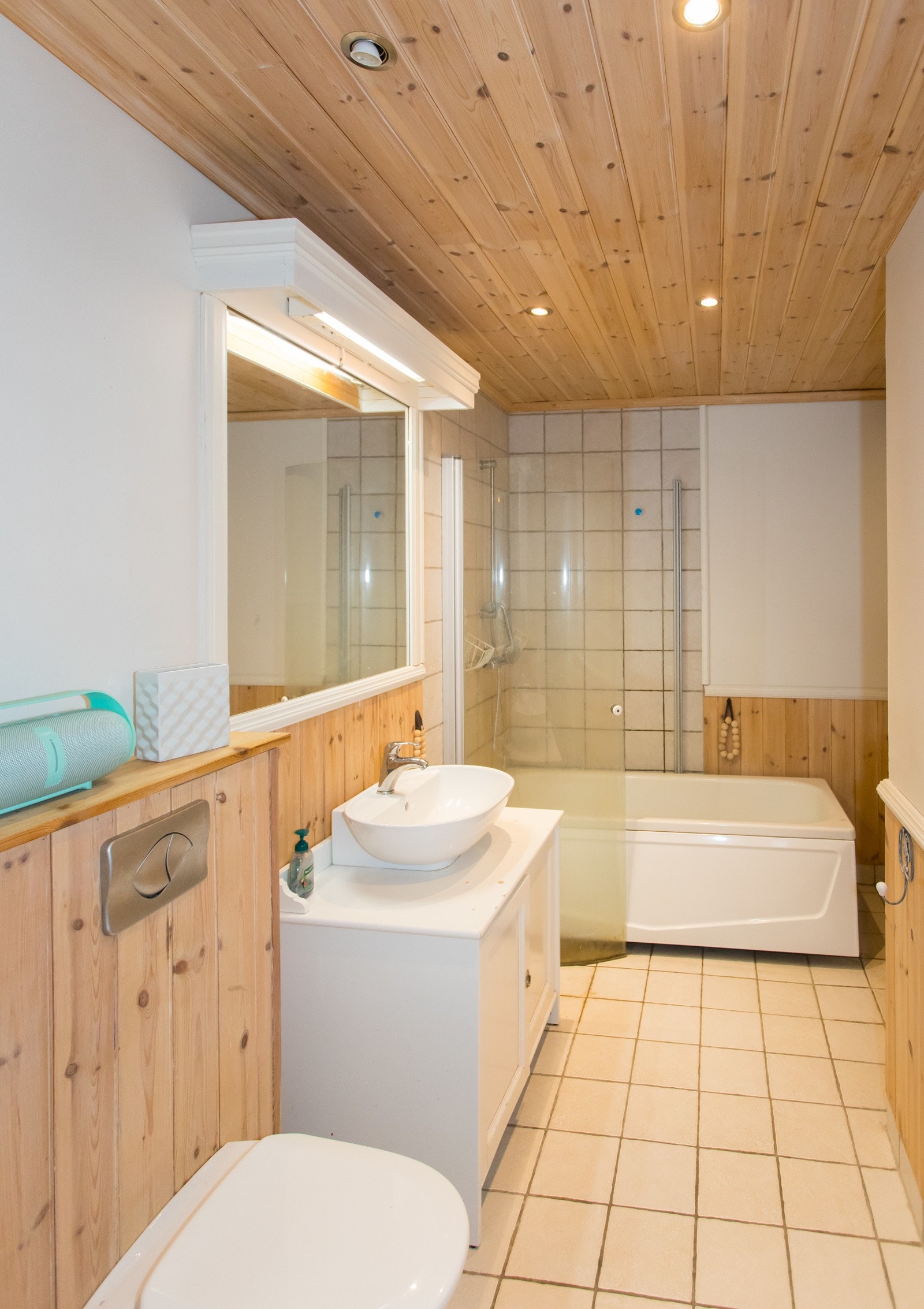 Bad i boligdelen. Badet er innredet med fliser på gulv, baderomsinnredning, toalett og badekar med dusjløsning. Galleribilde