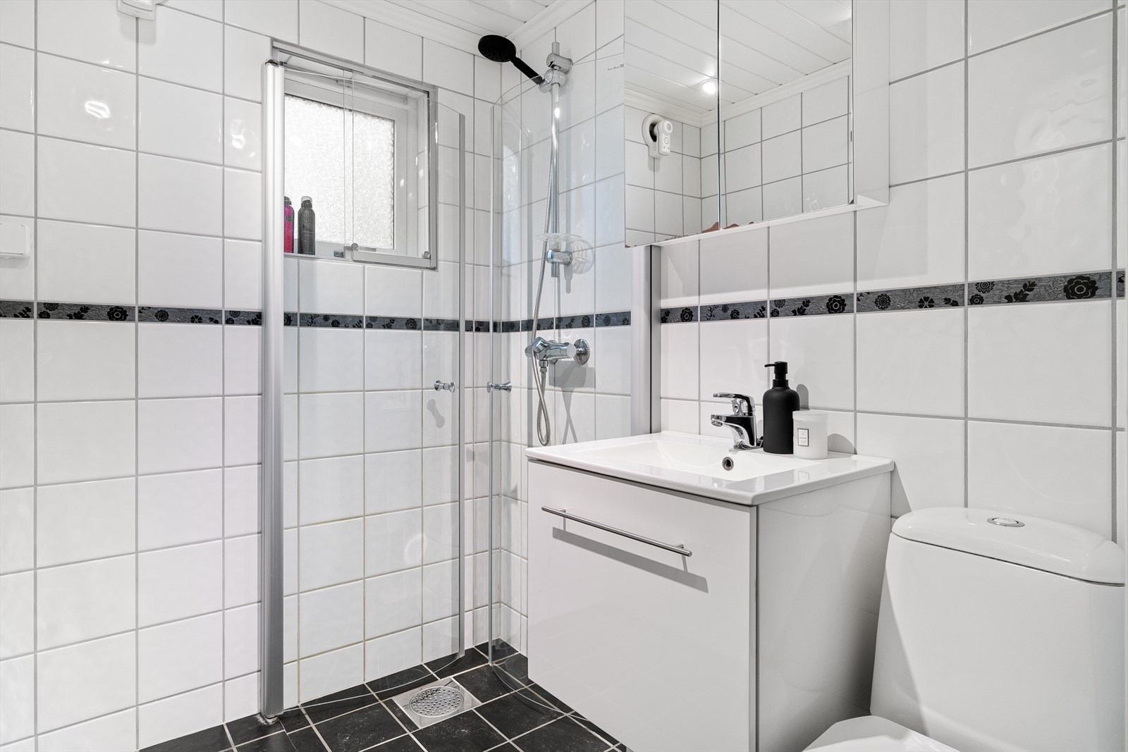 Badet inneholder innredning med servant, speilskap, toalett og dusjhjørne med innfellbare dusjdører. Det er også opplegg for vaskemaskin på badet. Galleribilde