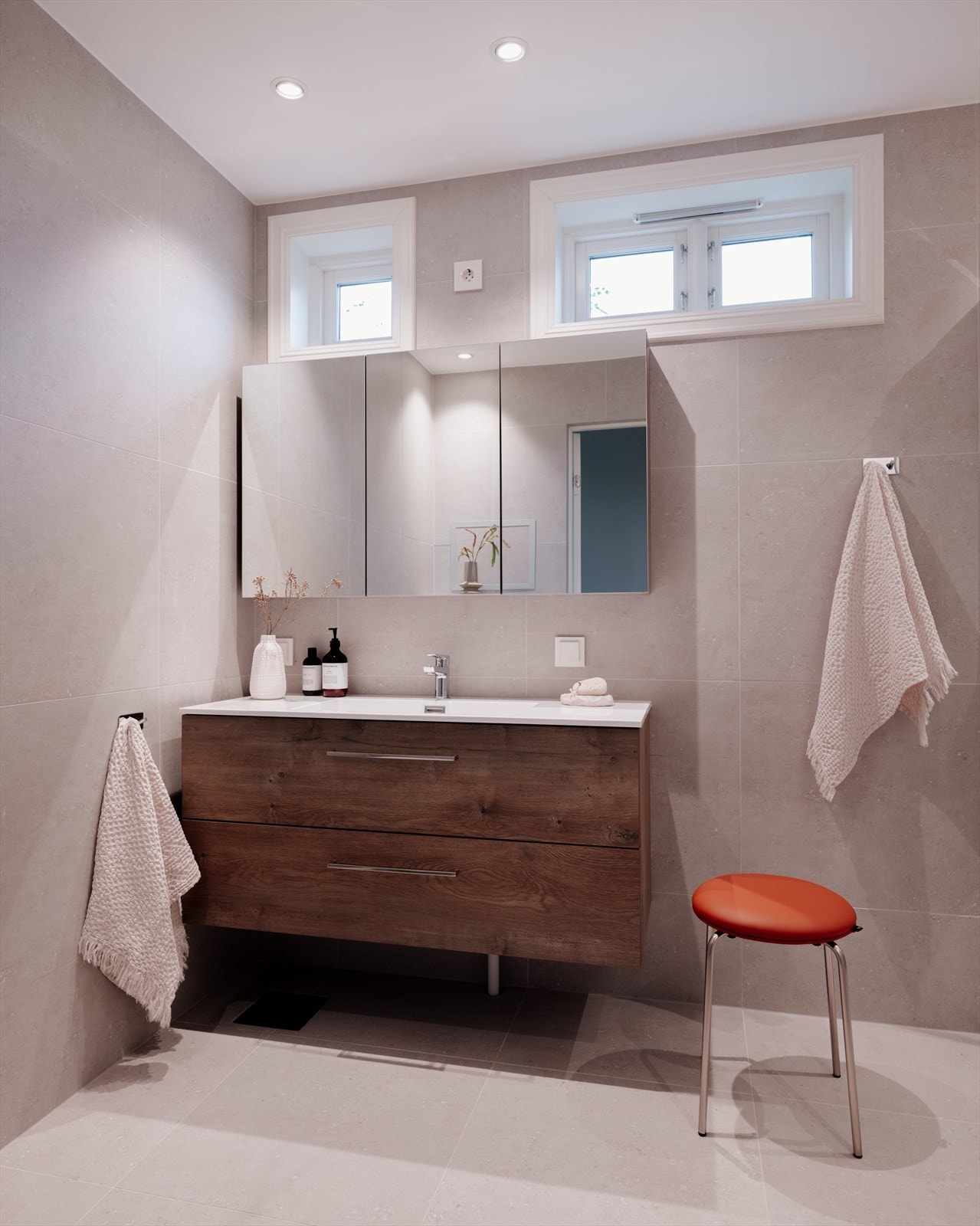 Badet er innredet med dusj med vannfallsdusj, hånddusj og glassdører, frittstående badekar, helstøpt servant i innredning med skuffer under, skap med speil, samt vegghengt toalett Galleribilde