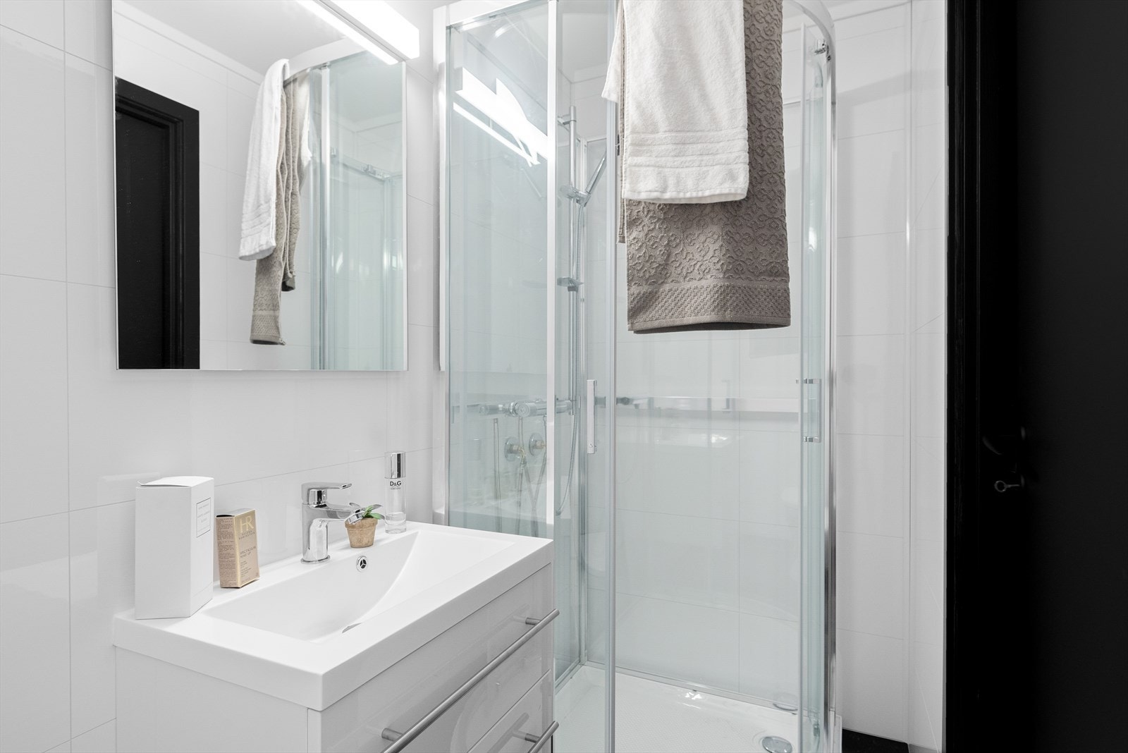 Badet er pusset opp i 2023 og fremstår som moderne og lekkert. Det er overflater av belegg på gulv og hvite våtromsplater på vegger. Galleribilde