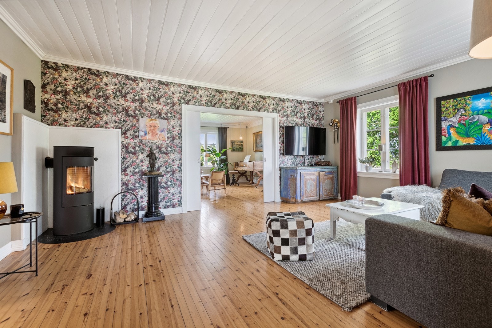 En skjermet og lun tv-stue med plass for sofamøblement, en dagligstue med peisovn og en spisestue innenfor kjøkkenet. Galleribilde