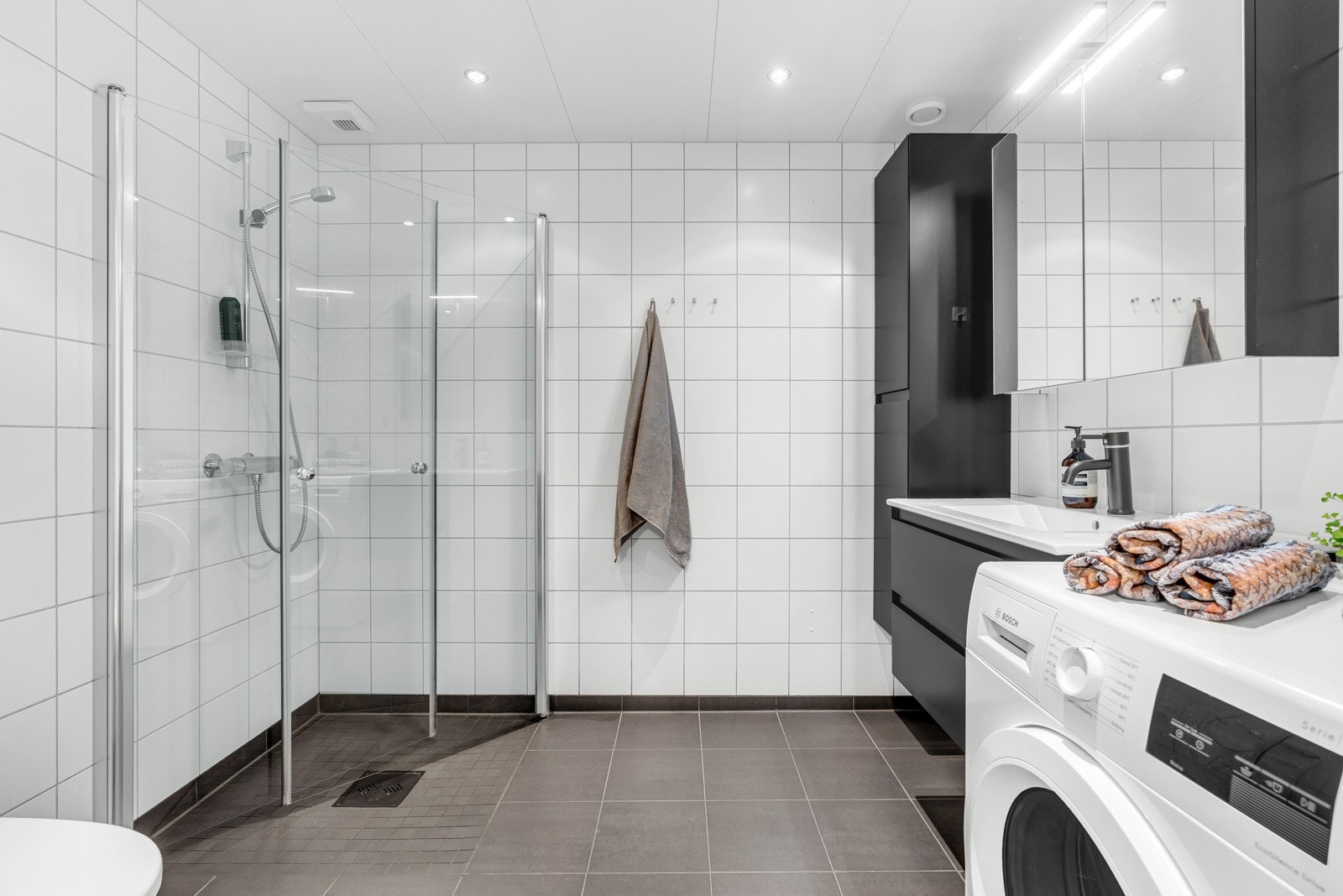 Stort bad med tidløst flisvalg, downlights i himling, varme i gulv og godt med plass til vaskemaskin. Galleribilde