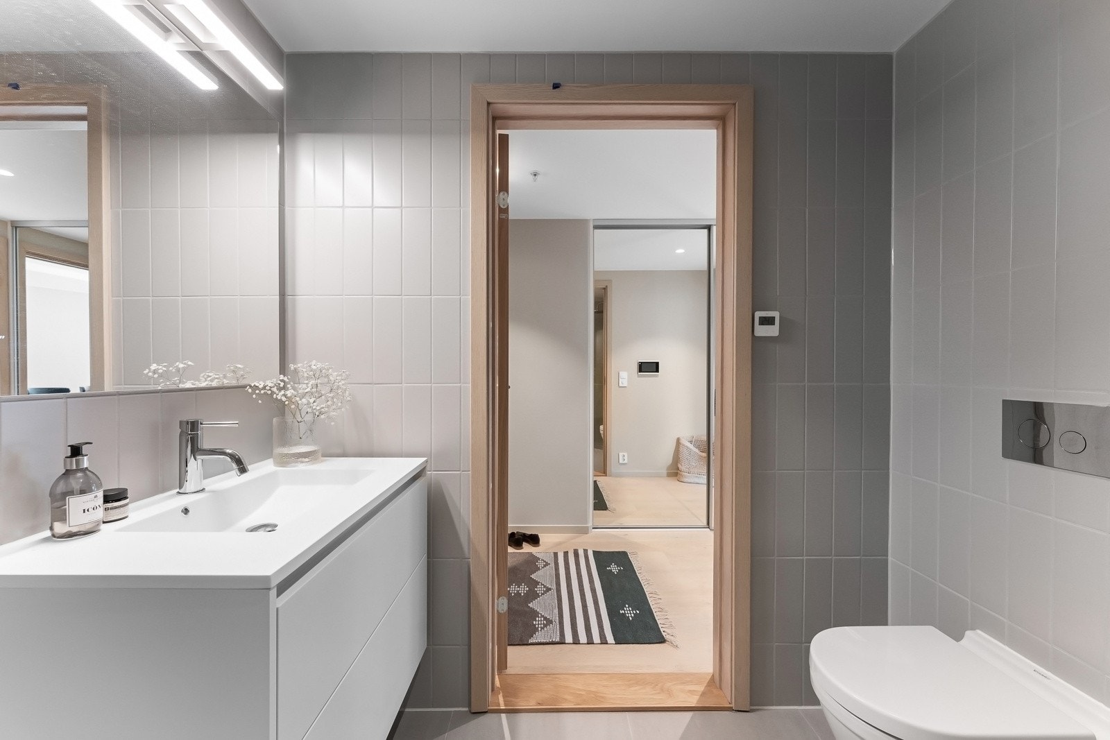 Badet som ligger tilknyttet entreen er utstyrt med veggmontert toalett, nedsenket dusjhjørne med innfellbare dører og regnfallsdusj, samt opplegg for vaskemaskin. Galleribilde