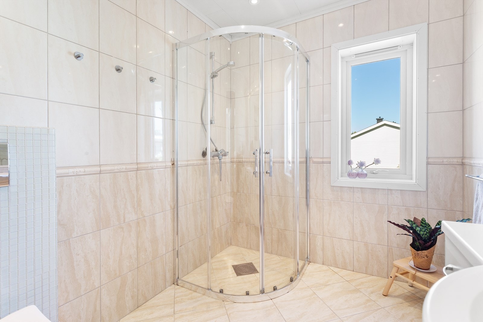 Badet er utstyrt med vegghengt toalett, servant med skap og dusjnisje med kabinett. Galleribilde