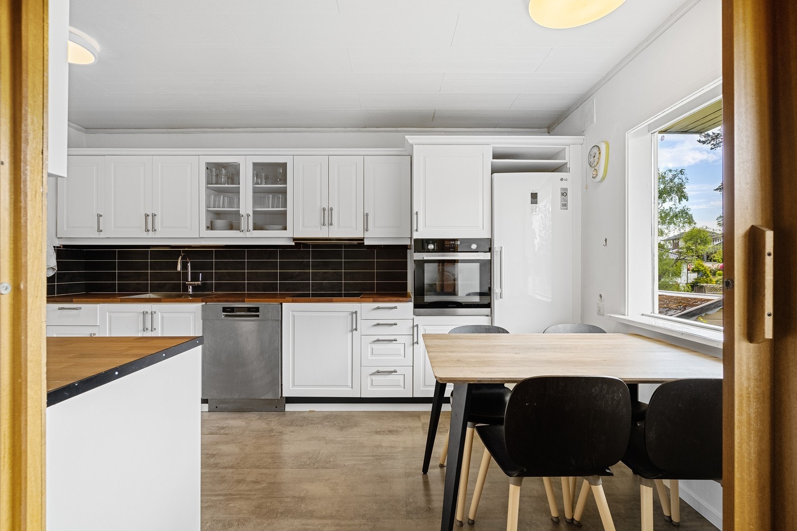 Kjøkkenet er i en moderne tosidig løsning og i hvit utførelse. Galleribilde