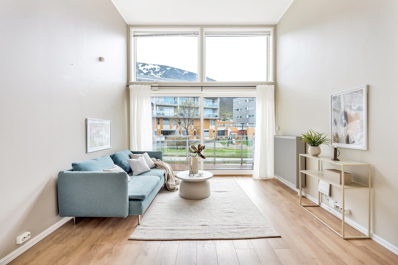 Stue med meget sjenerøs takhøyde samt store vinduer som slipper inn mye naturlig lys gir god romfølelse Galleribilde