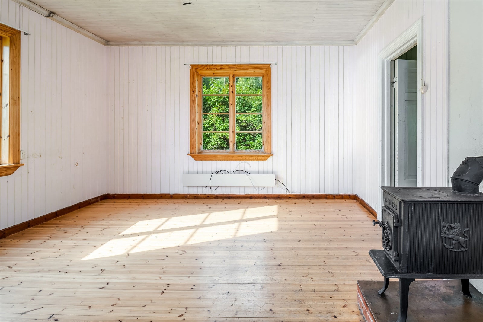 Stuen er romslig med plass til det man skulle ønske og trenge av møblement. Tre store vinduer slipper høstsolen flott inn. Galleribilde