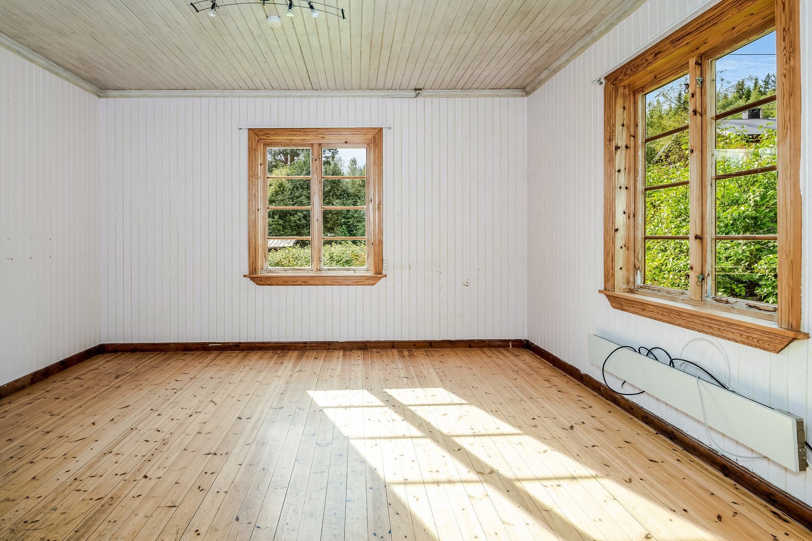 Stuen har hvitmalt panel på veggene, malt panel i himling og tregulv. Galleribilde