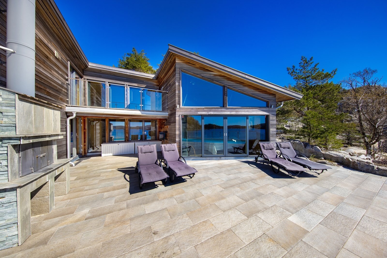 Vakre uteområder. Legg merke til utegrillen, samt boligens store vindusflater. Galleribilde