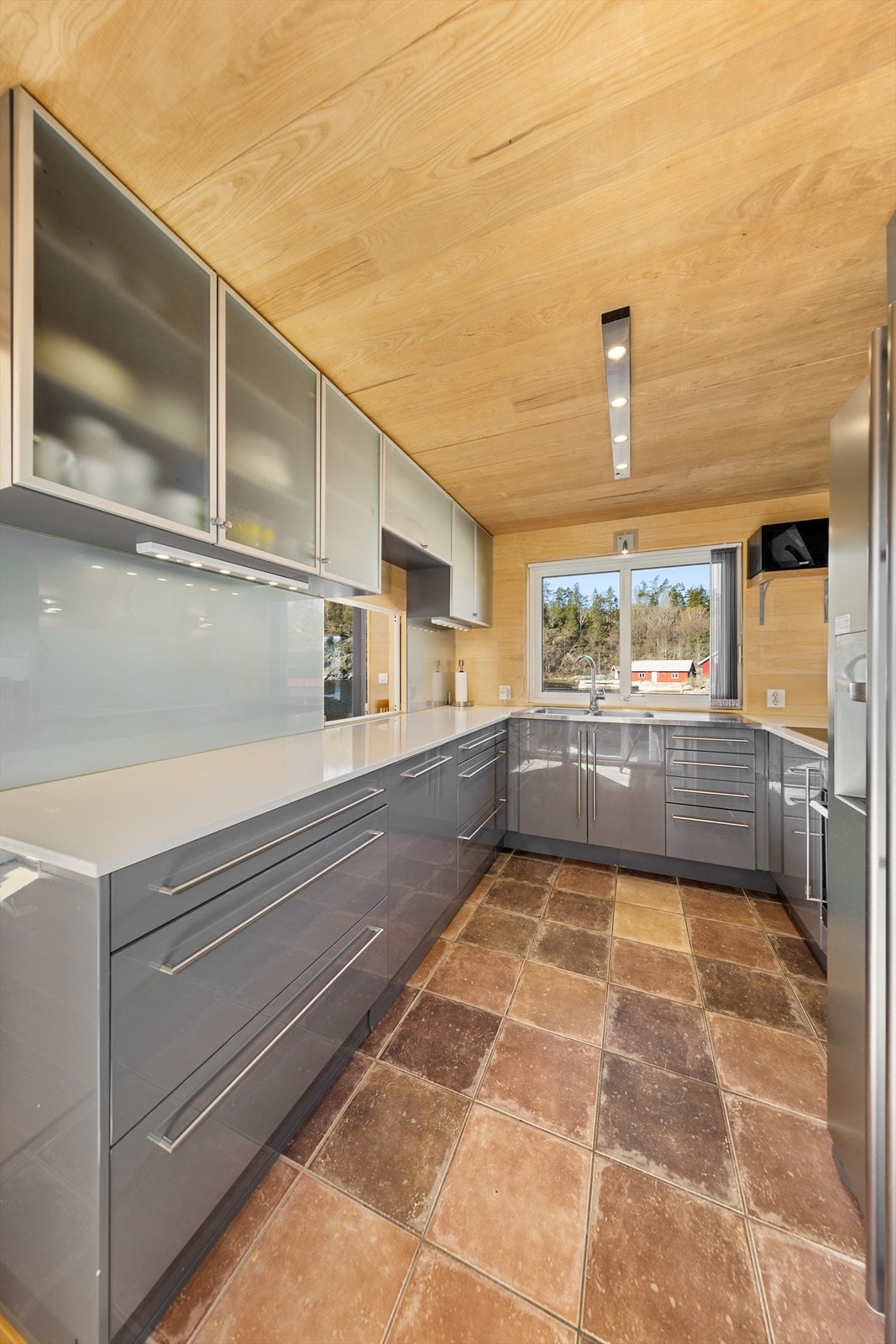 Lekkert og moderne kjøkken med grå fronter og benkeplate i kompositt. Galleribilde