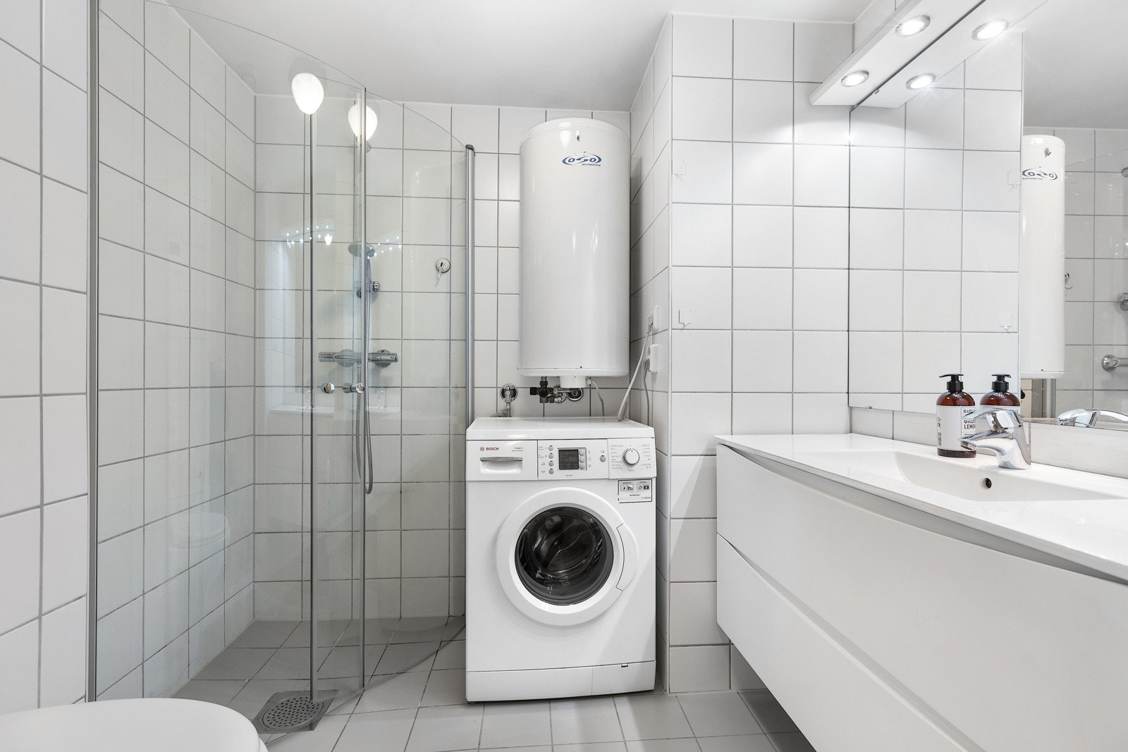 Flislagt baderom underliggende varmekabler. Badet er utstyrt med skuffesekjson, nedfelt servant, og speil med tilhørende belysning. Galleribilde