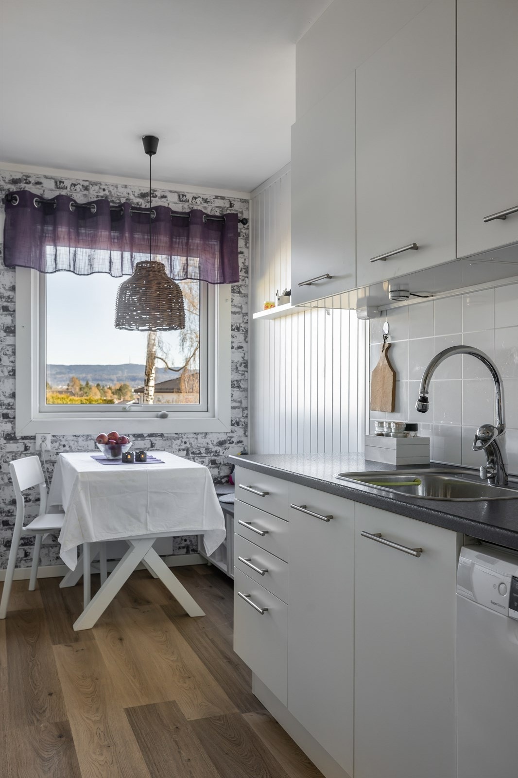 Kjøkkenet har lys innredning med glatte fronter og benkeplater av laminat med KitchenBoards over. Galleribilde