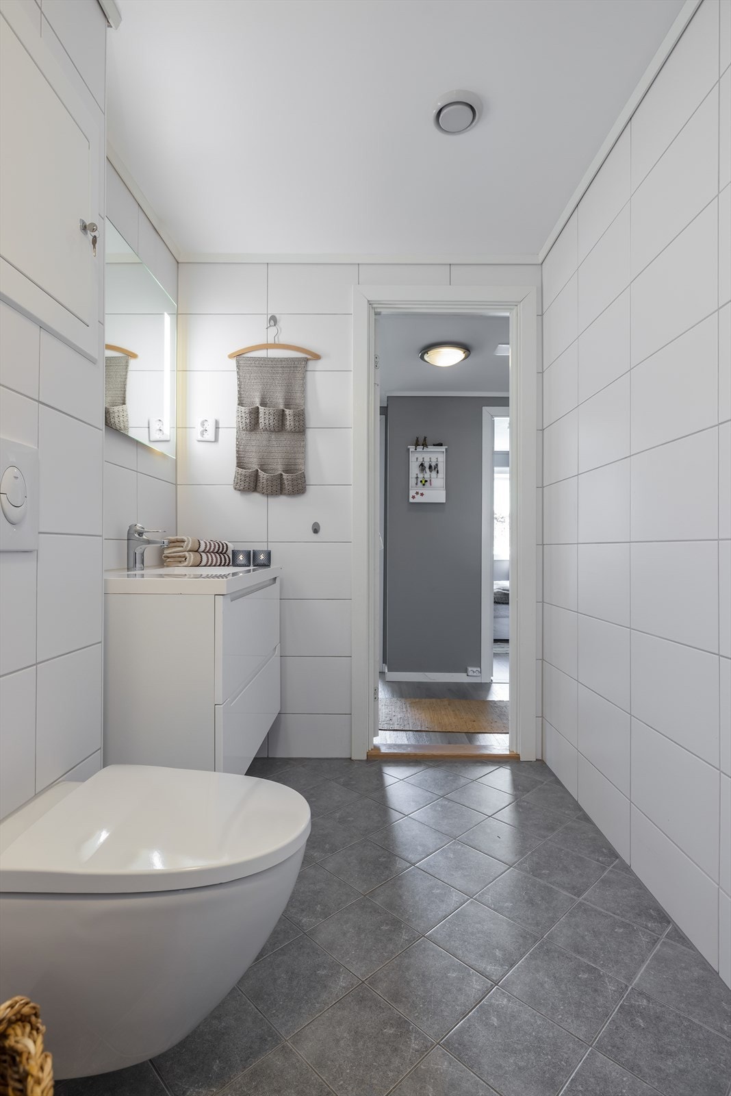 Badet inneholder veggmontert toalett, dusjkabinett og servantinnredning med underskuffer og speil med lys. Galleribilde