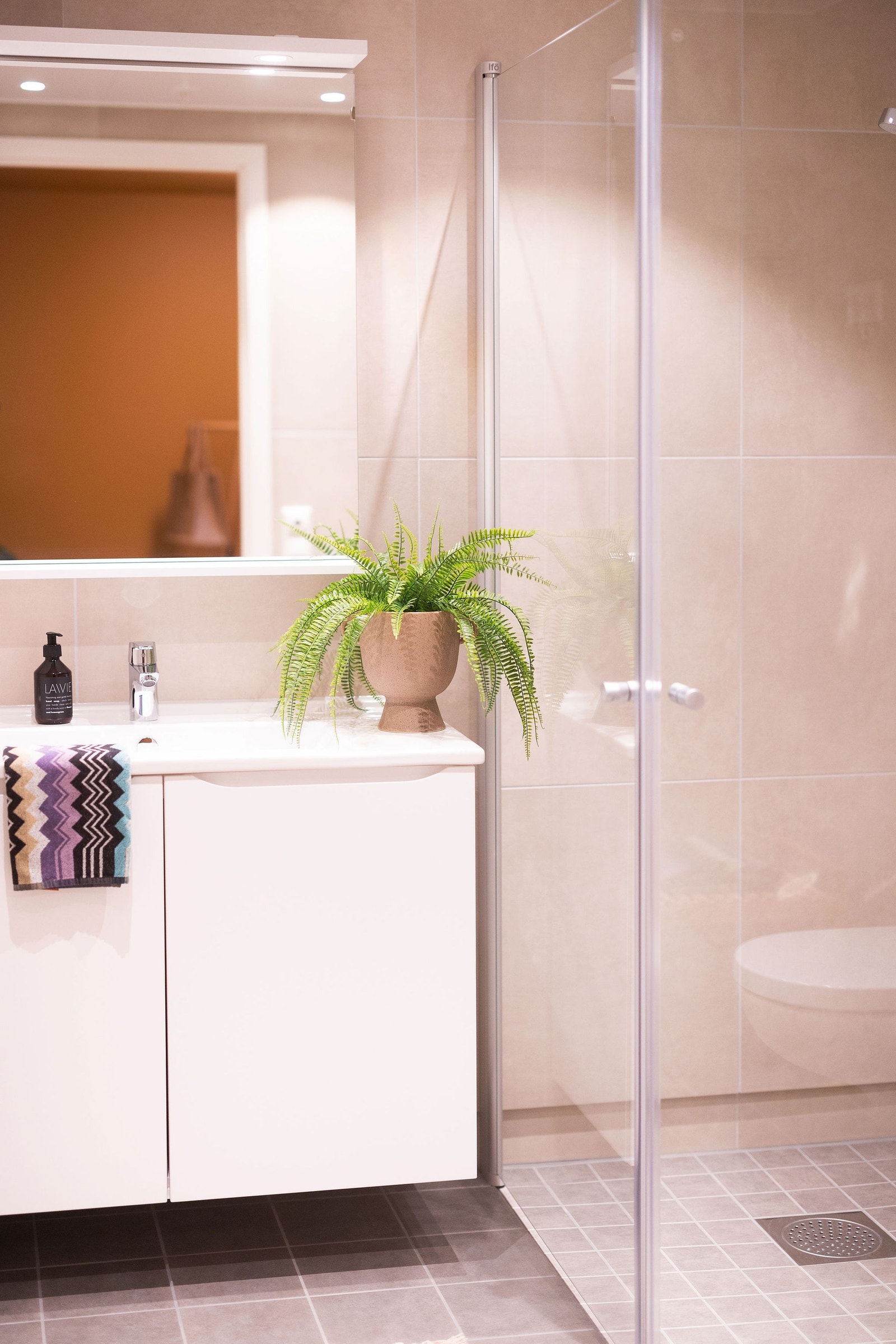 Flott, flislagt bad med veggehengt toalett, opplegg for vaskemaskin og spotbelysning i tak Galleribilde