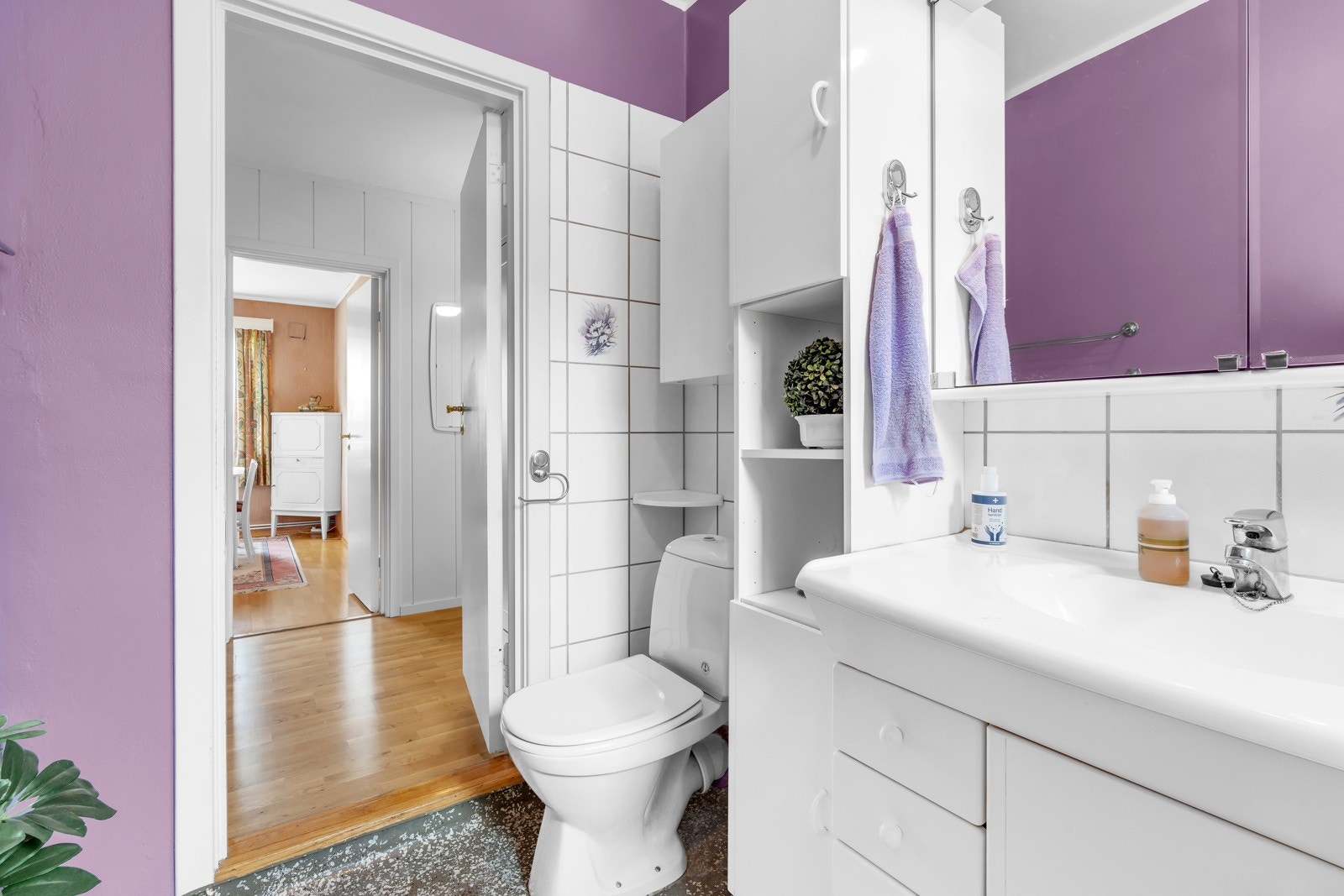 Badet inneholder servant med underskap, høyskap, speil med overlys og stikkontakt, badekar og gulvstående toalett. Galleribilde