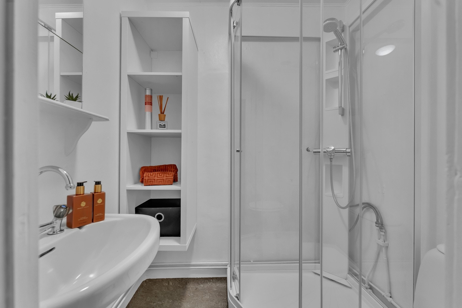 Baderom i loftsetasjen er trolig fra byggeår og har gulvflater med gulvbelegg og malte overflater på vegger. Høyskap og servant med to greps armatur, speil på vegg, frittstående toalett og dusjkabinett med ett-greps armatur med hånddusj. Galleribilde