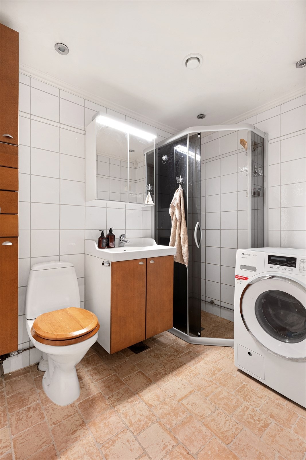 Innredningen består av gulvmontert wc, dusjsone med skyvedører, samt servant med underskap, overskap, speil og belysning. Galleribilde