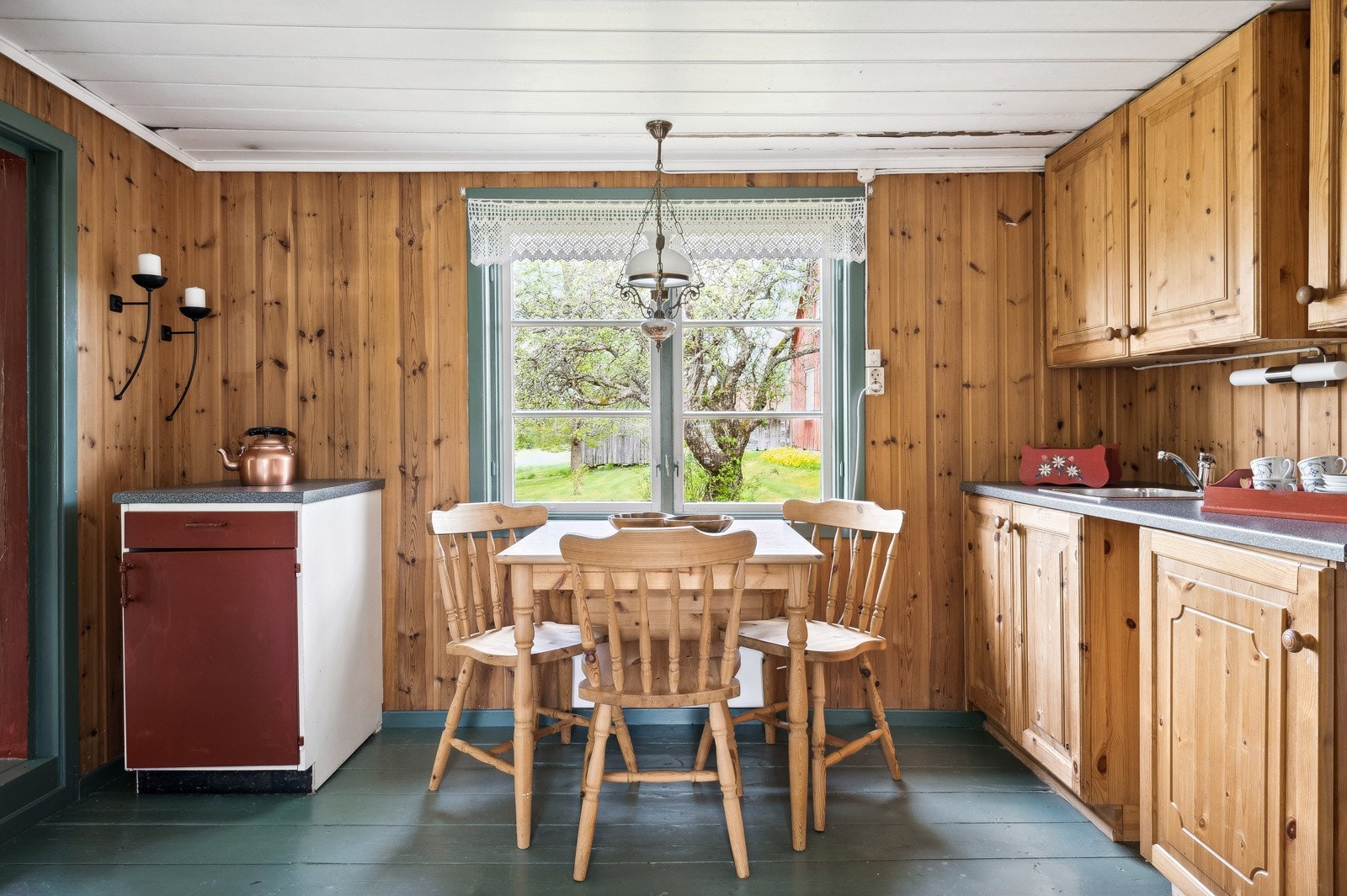 Kjøkkenet i kårboligen har panelvegger, malt tregulv og takhøy innredning med trehvite fronter. Galleribilde