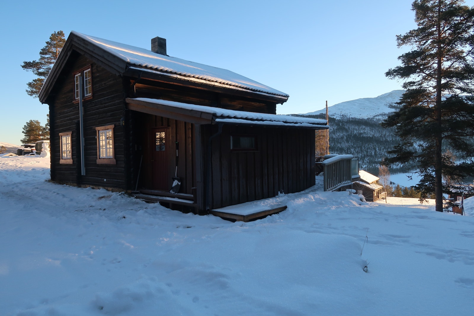 Gressplen på begge sider av hytta. Terasse med kveldssol. Galleribilde