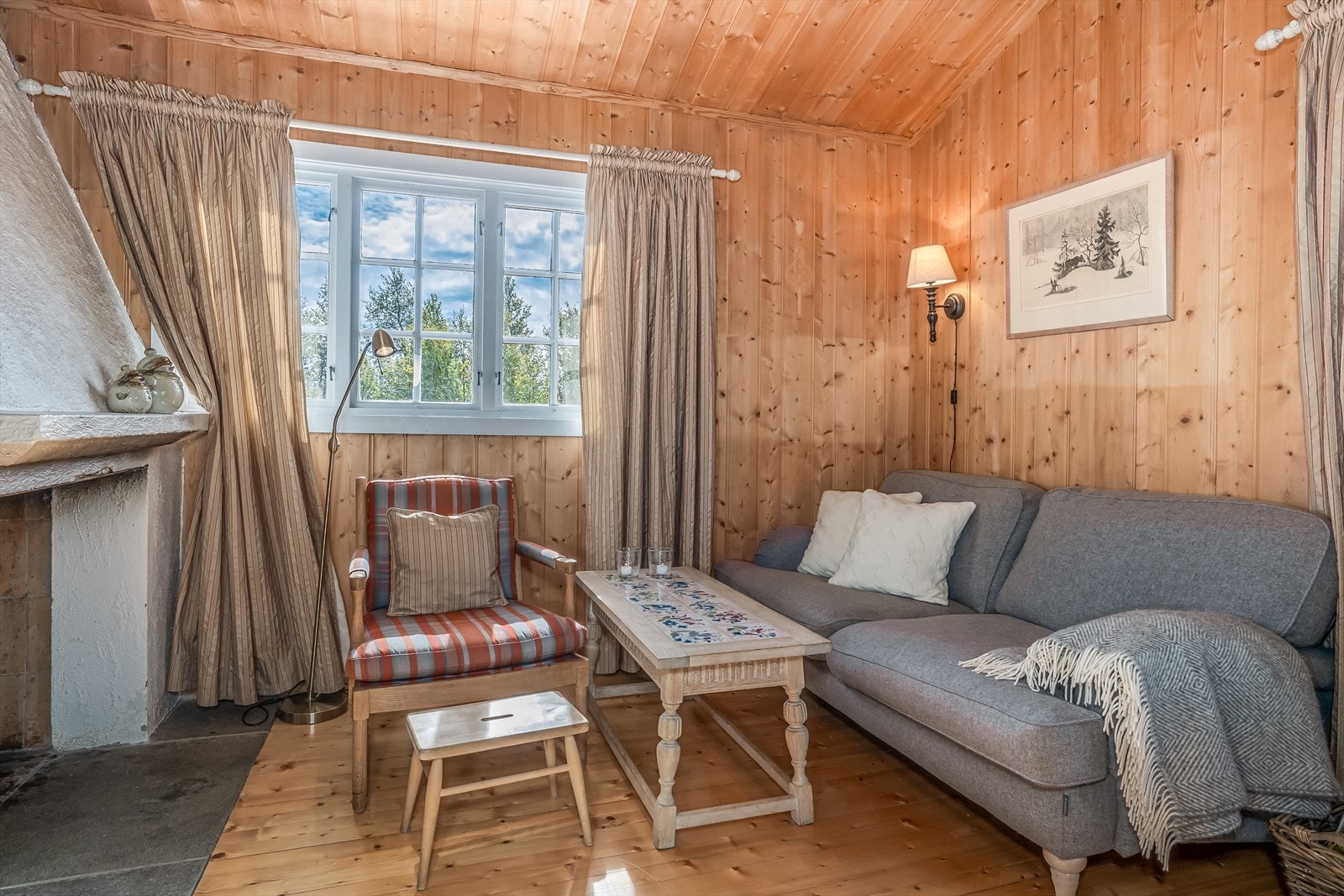 Stue med panelte vegger, tregulv og himling med god takhøyde og synlige åser. Galleribilde