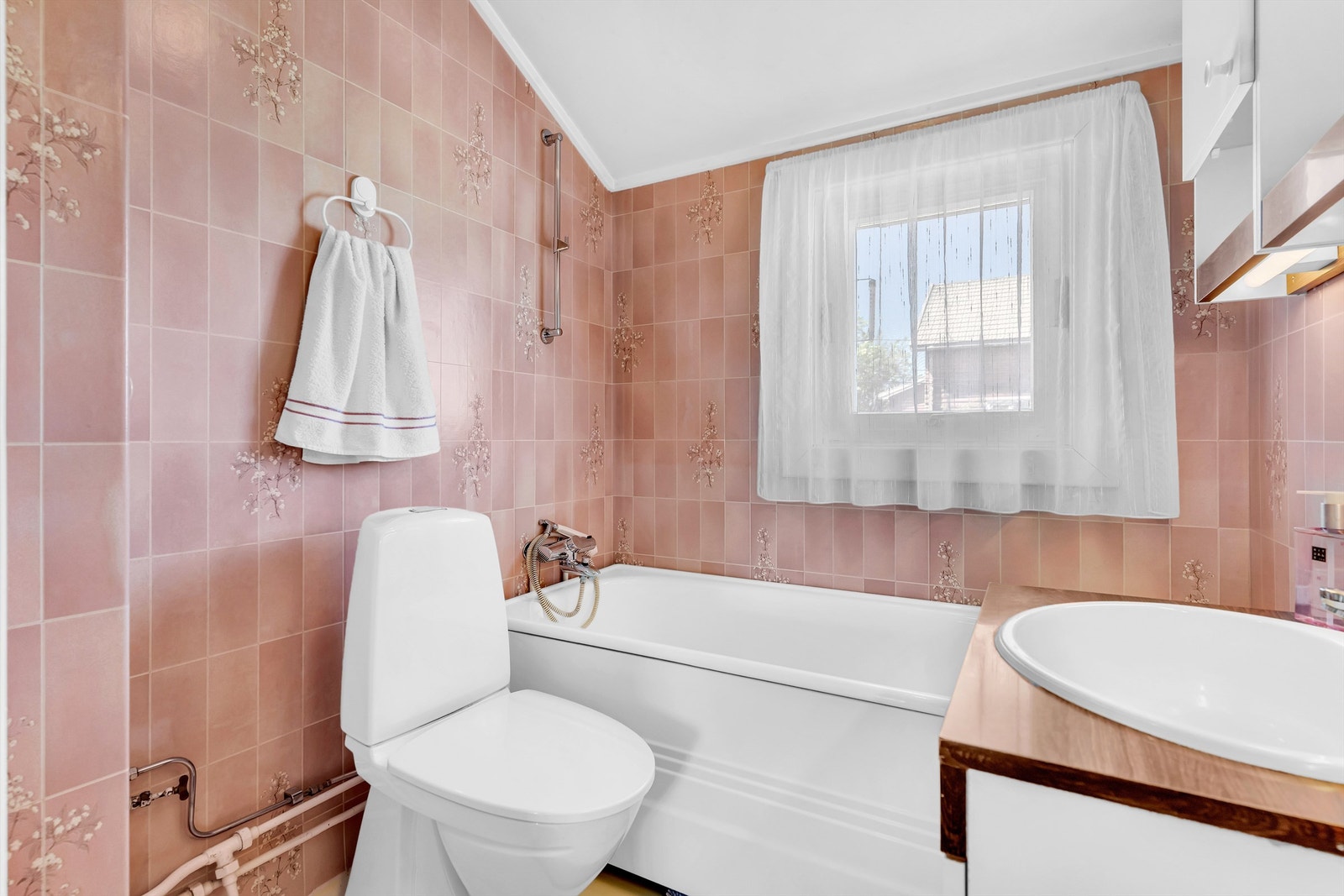 Badet er fra byggeår med gulvbelegg og våtromstapet på vegger Galleribilde