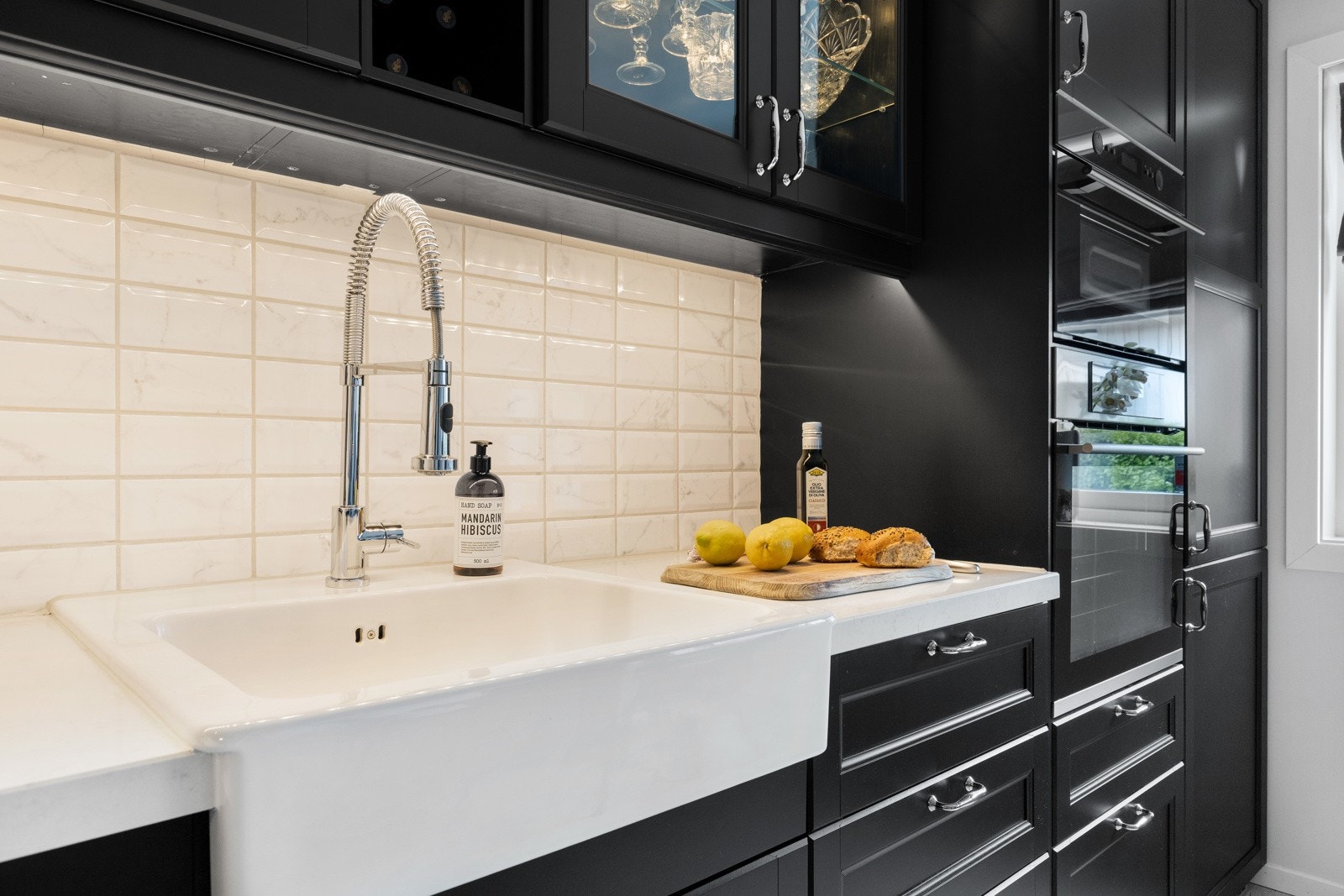 Over benken er det lyse fliser som backsplash, og over kokesone har du ventilator. Galleribilde