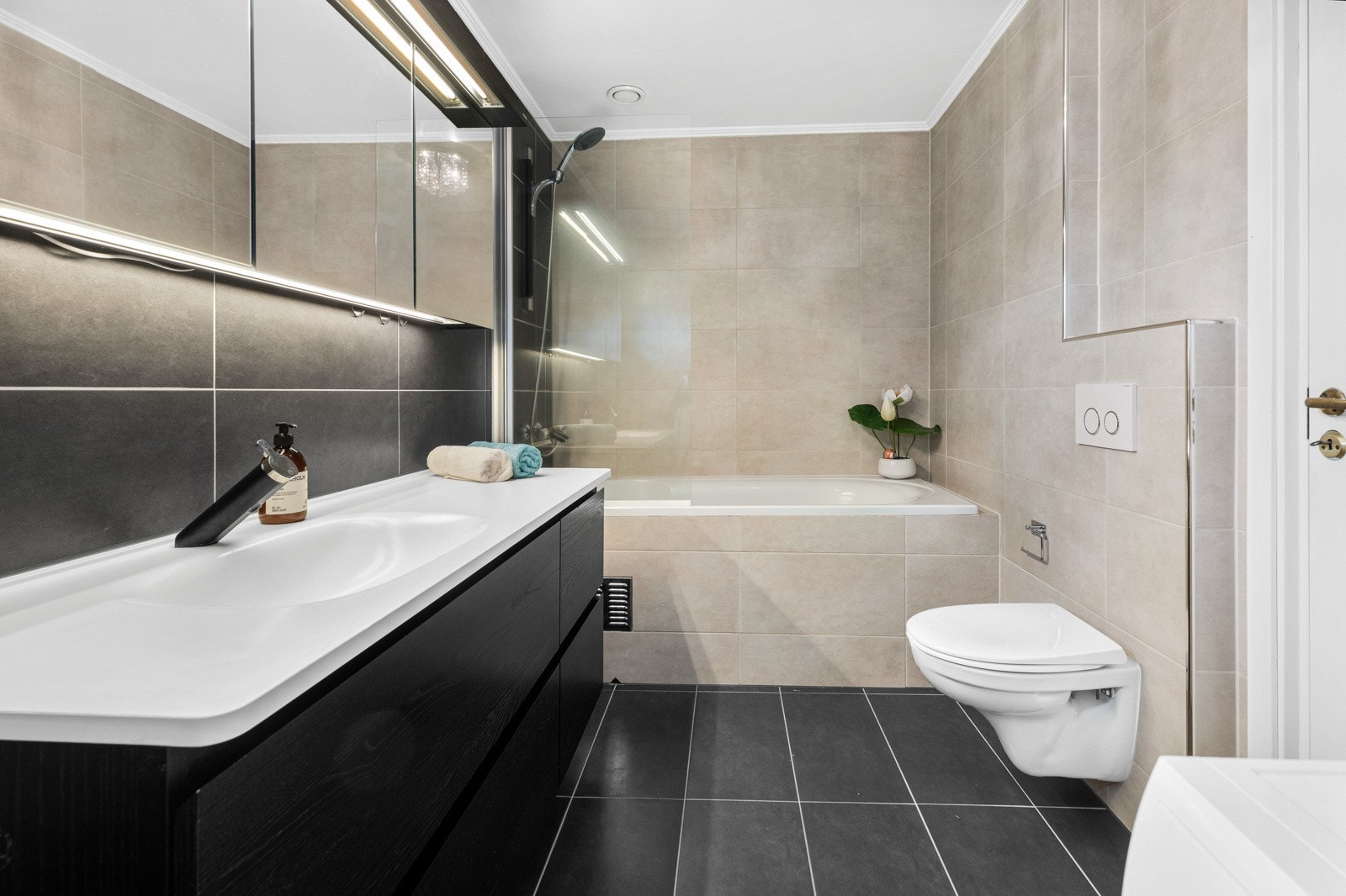 Badet har innfliset badekar med dusjvegg og dusjgarnityr, og det er også fliser på gulvet og veggene. Galleribilde