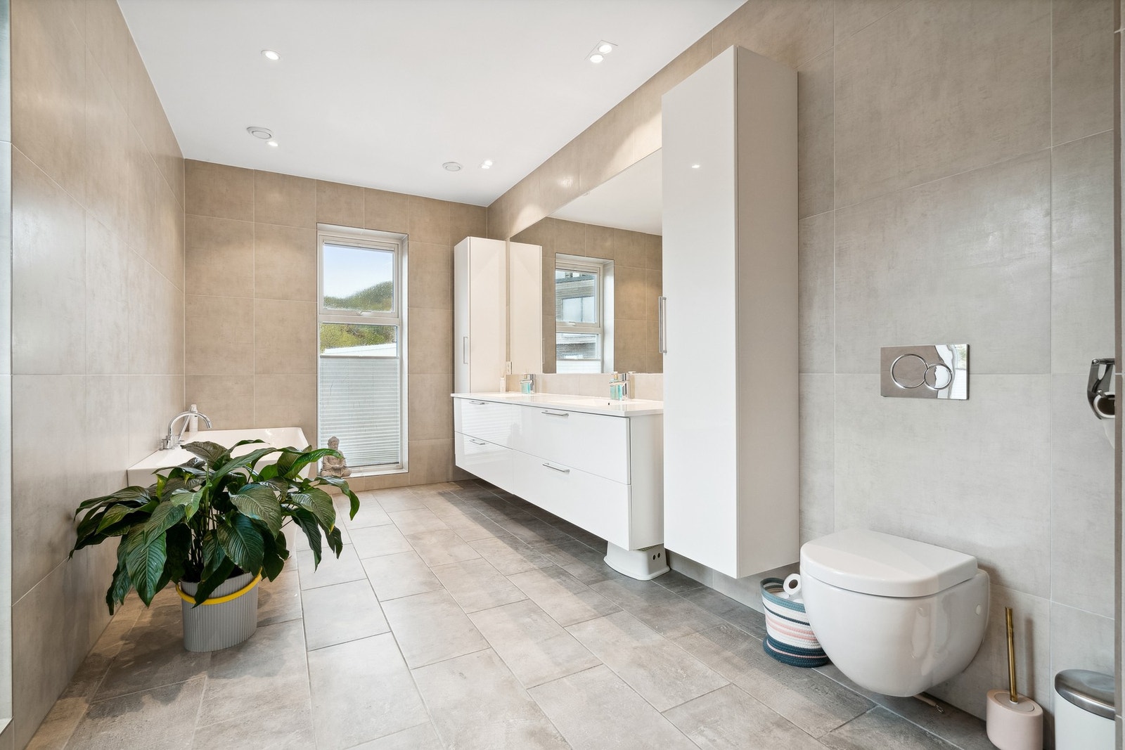 Vegghengt toalett og moderne baderomsinteriør med stor speilflate Galleribilde